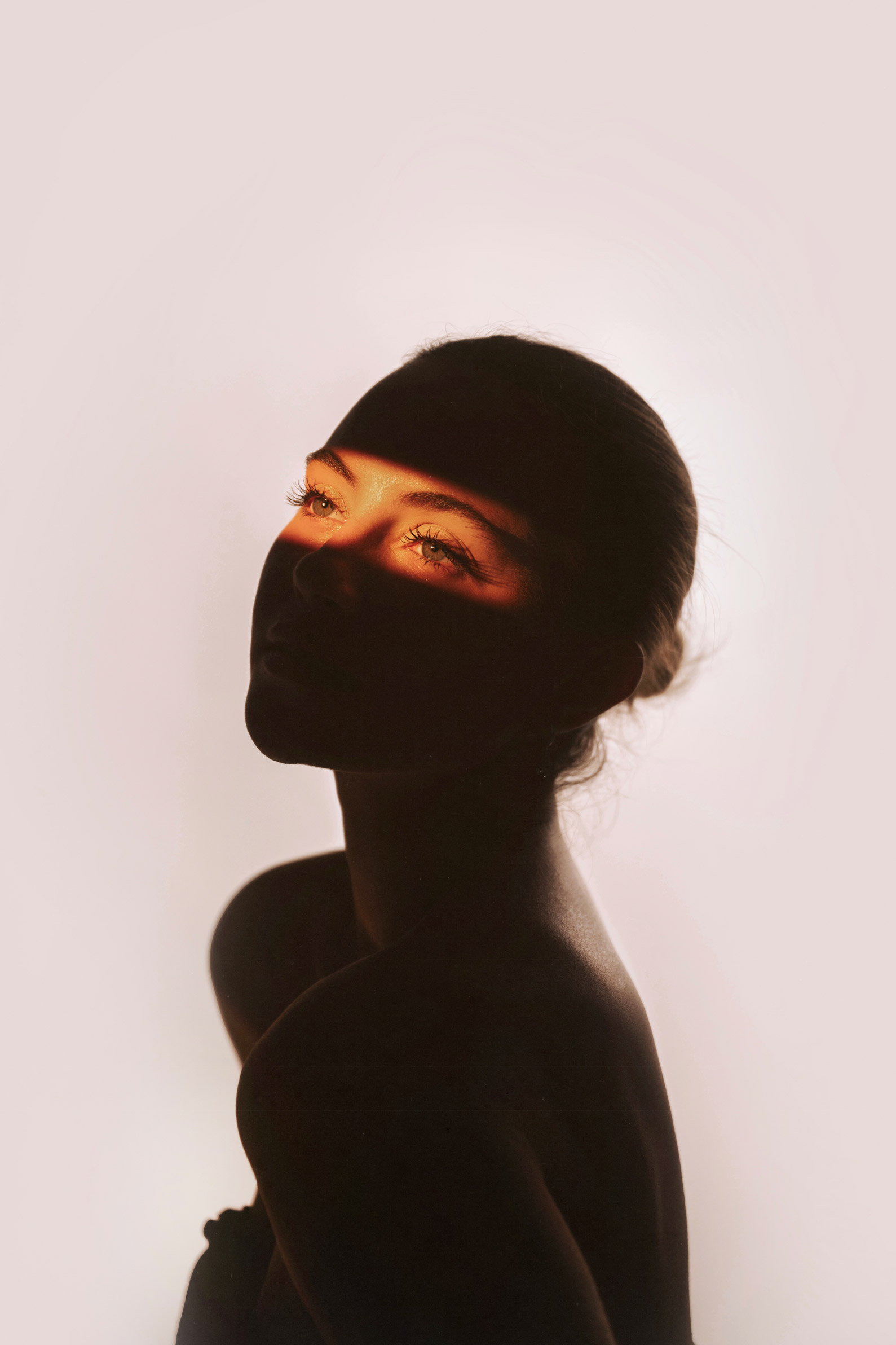 Iemand kijkt omhoog met een sprankje gouden licht op zijn gezicht, foto door Brandon Woelfel
