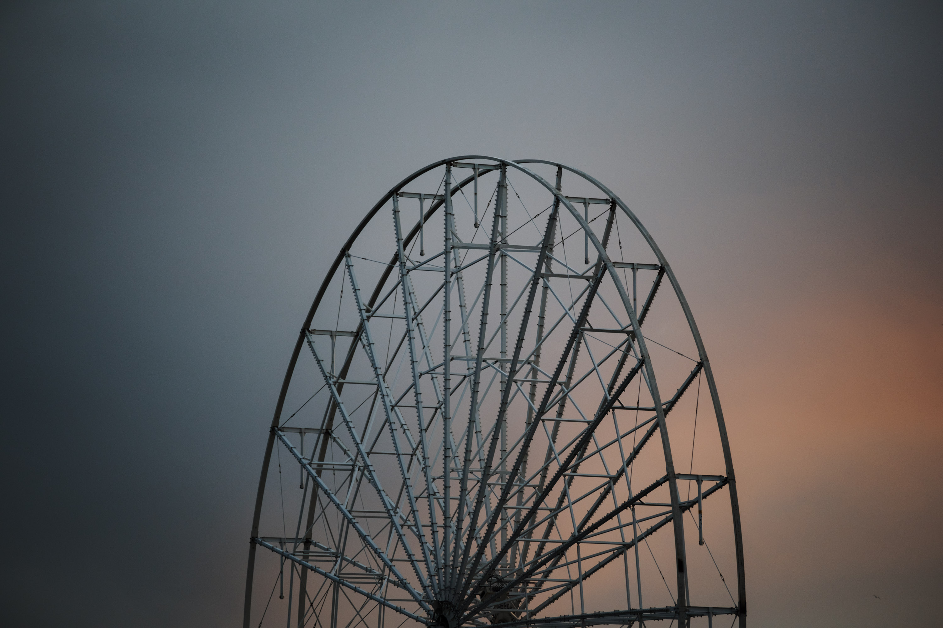 La moitié supérieure d'une grande roue grise sans sièges sur fond de ciel gris-jaune, photographiée avec un Fujifilm X-T5.
