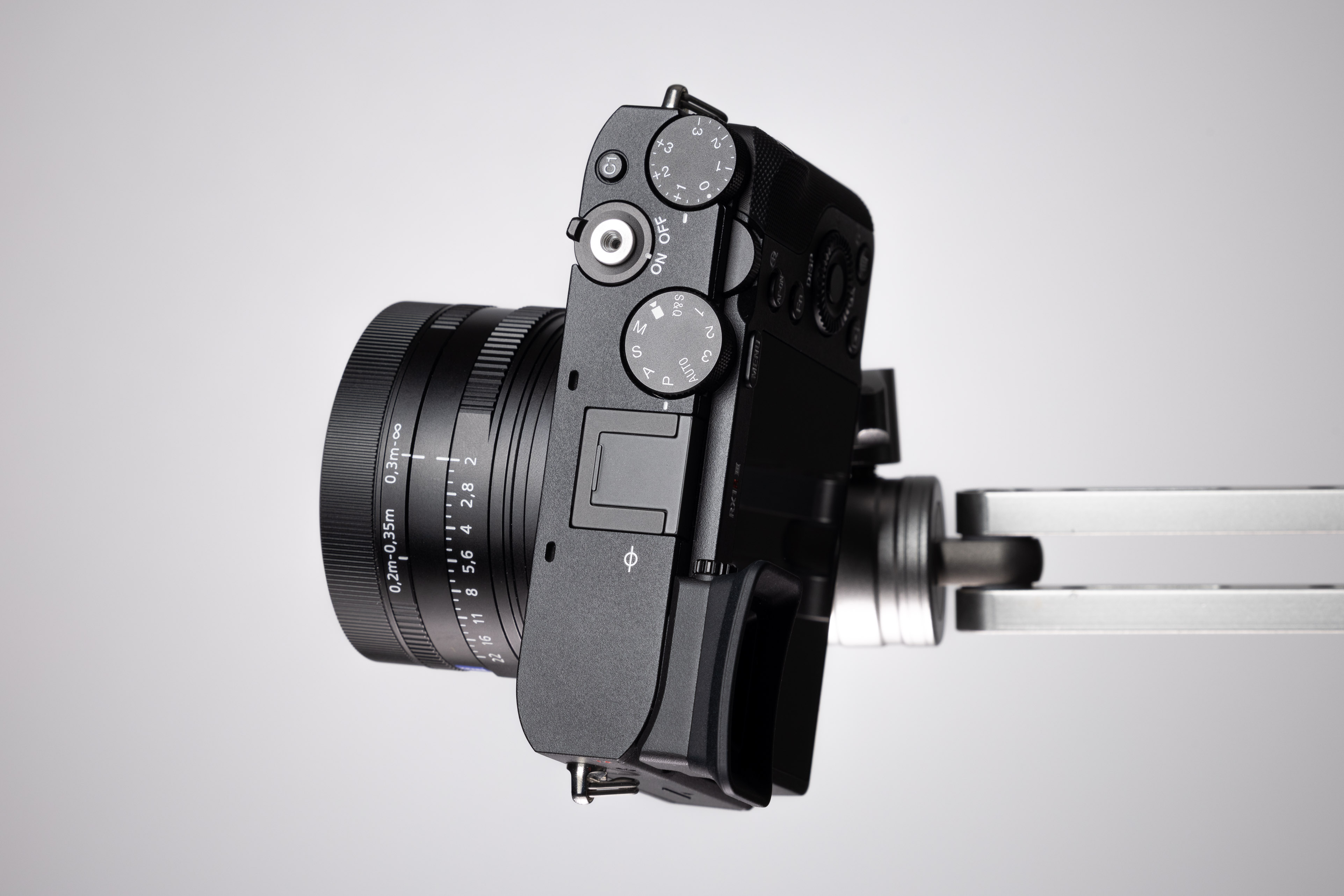 Draufsicht einer schräg auf einem Metallarm montierten Sony RX1R III mit dem festen 35-mm-Objektiv, Blendenring, Belichtungsrädern und dem minimalistischen Bedienfeld auf der Deckplatte.