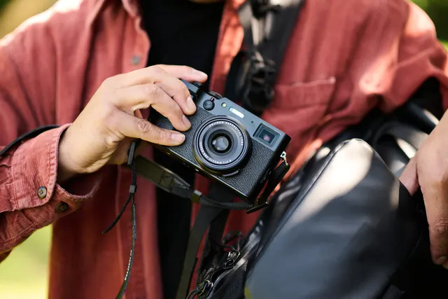 A person putting a small camera in a camera bag. 