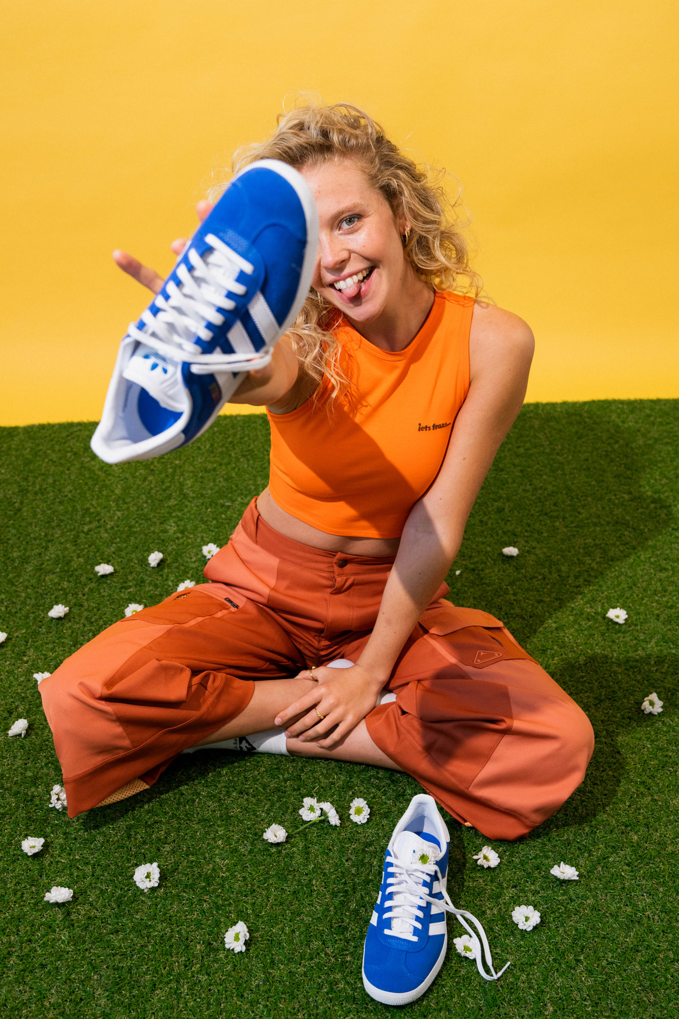 Ein Bild von einer Frau im Schneidersitz, die einen blau-weißen Schuh in die Kamera hält, fotografiert von Anna Langer mit der Nikon D850.

