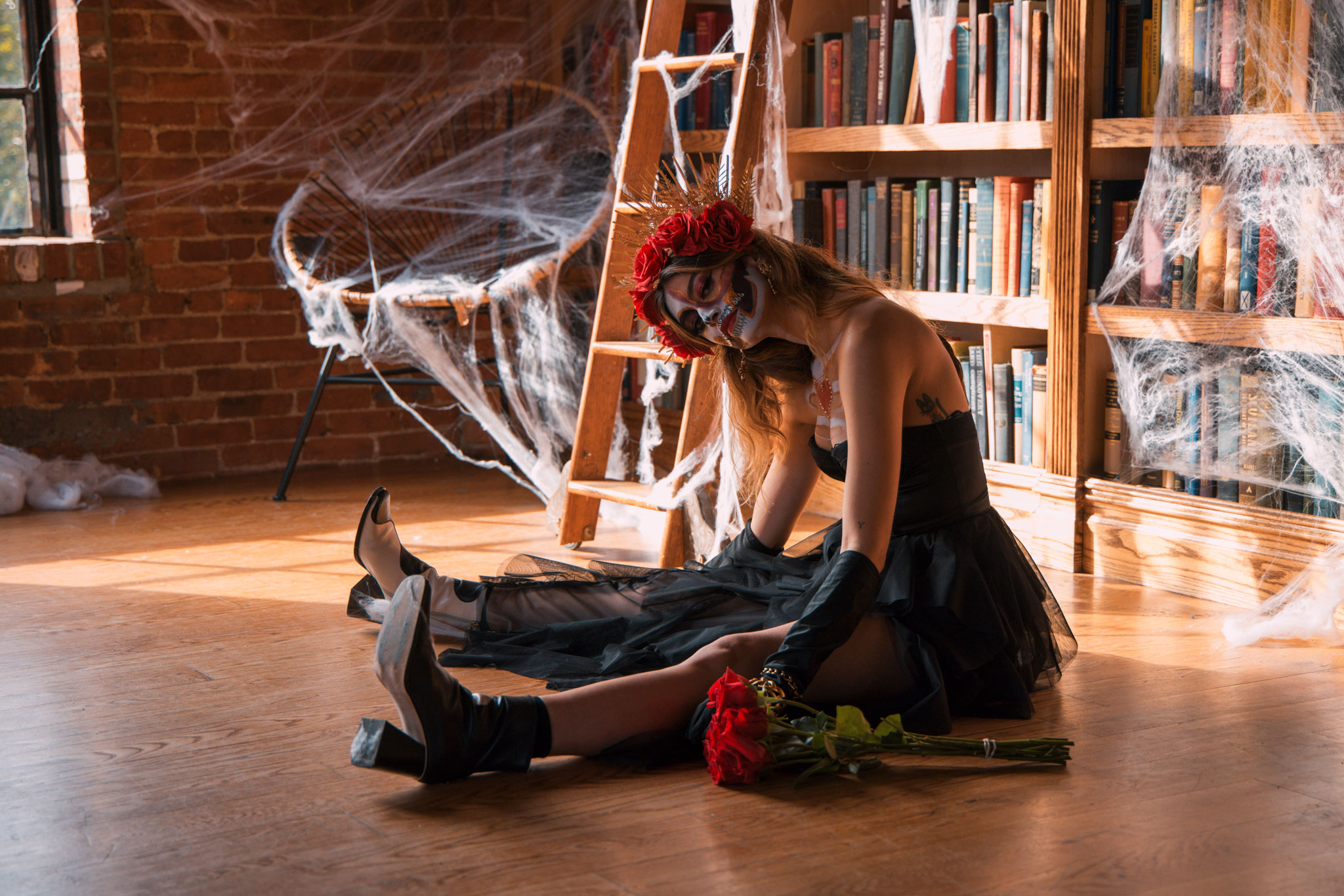 Day of the Dead cosplayer sits with a bouquet of red roses.

