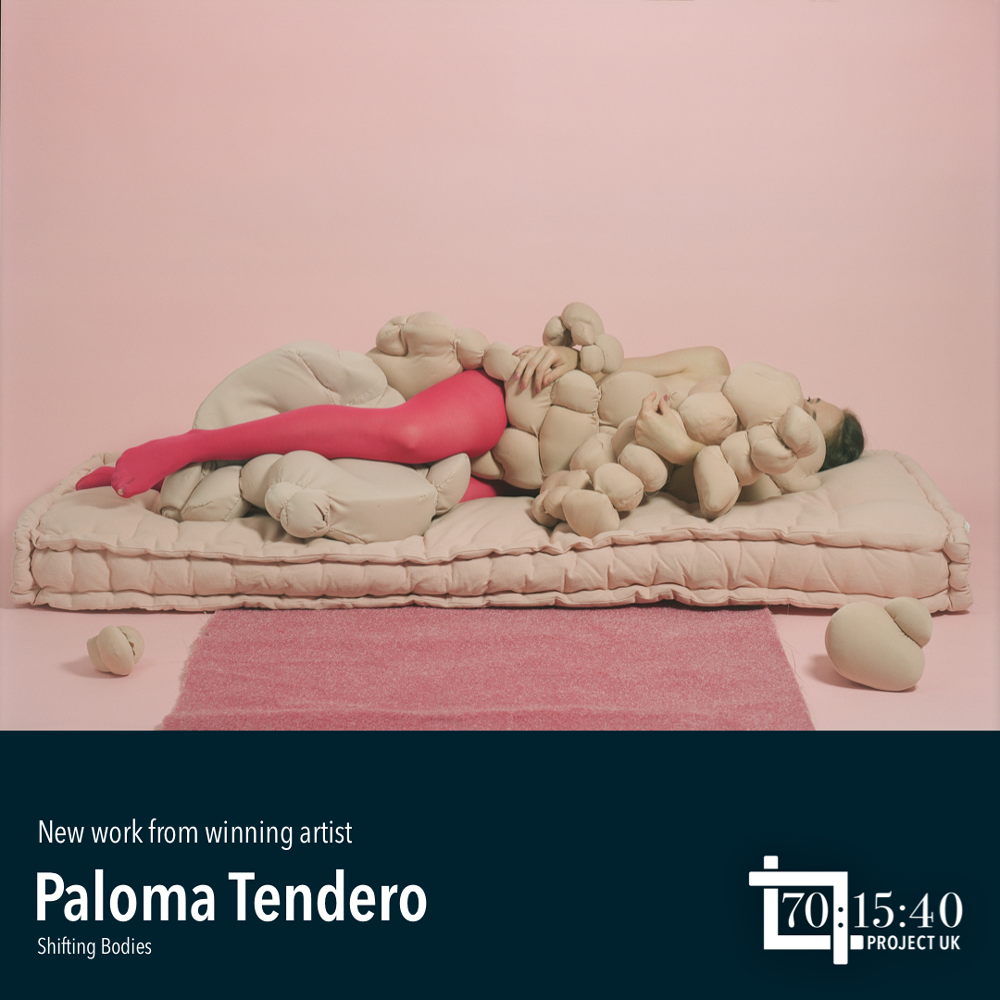 A model wearing dark pink tights lying on a mattress partially covered by fabric objects, photo by Paloma Tendero