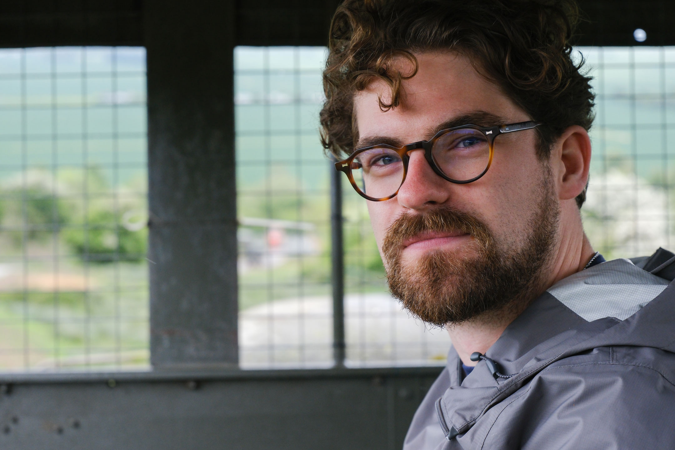 A portrait of Connor Redmond wearing glasses and a waterproof jacket at Port Lympne Safari Park, photo by Amy Moore with a Fujifilm X-T50