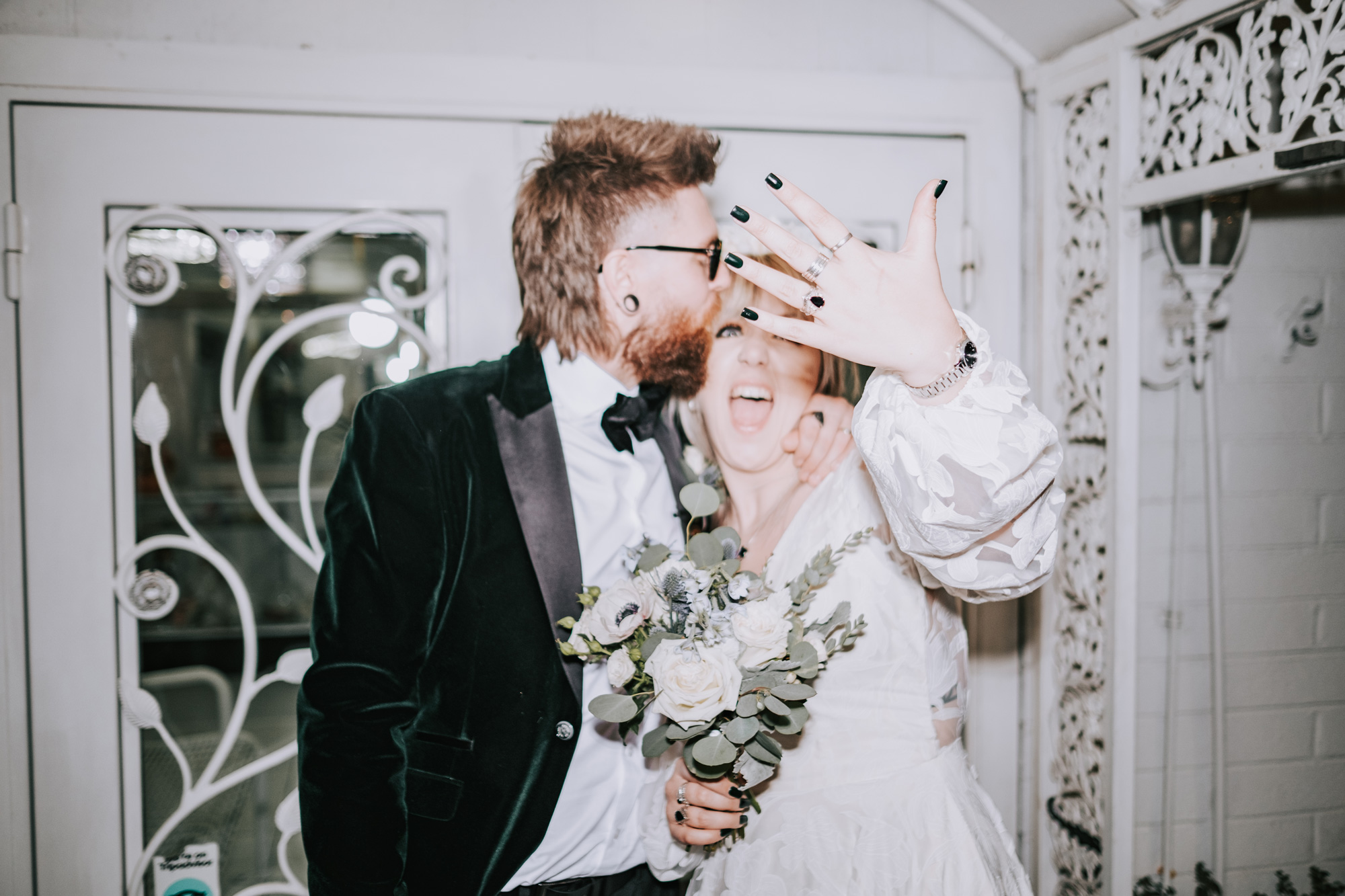A bride and groom at a wedding, the bride is holding a bouquet of flowers and showing off their ring, shot by Matthew Palmer with a Fujifilm X-T4