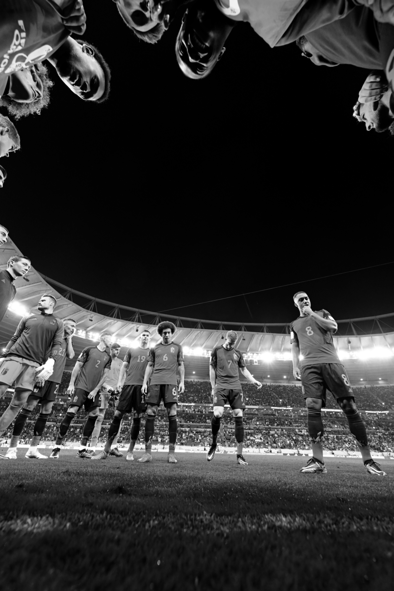 Ein Schwarz-Weiß-Foto der belgischen Mannschaft aus der Froschperspektive , die vor dem 1:0-Sieg gegen Kanada bei der Fußball-Weltmeisterschaft 2022 im Kreis steht, aufgenommen mit einer Nikon Z9 von Ryu Voelkel.