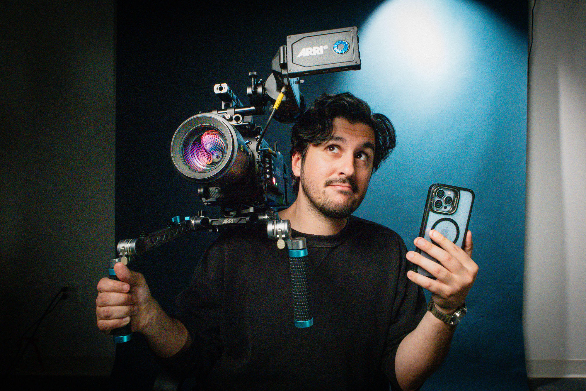 Une personne pose pour un test en haute sensibilité ISO en tenant une caméra de cinéma et un iPhone.