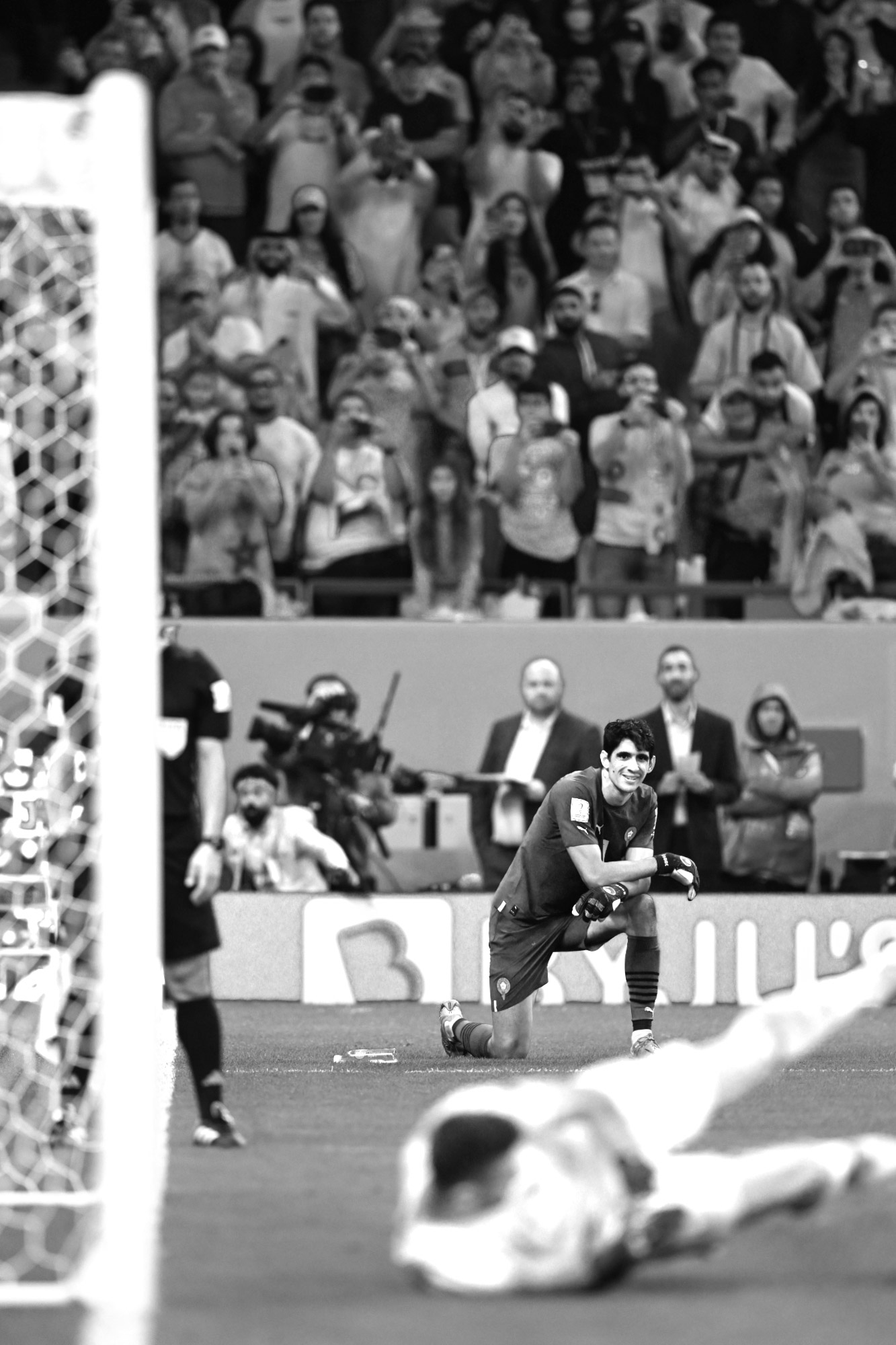 Ein Schwarz-Weiß-Foto des marokkanischen Torhüters Yassine Bounou, der lächelt und kniet, während der spanische Torhüter Unai Simón bei der Niederlage Spaniens im Elfmeterschießen im Achtelfinale der Fußballweltmeisterschaft 2022 einen Elfmeter nicht pariert, aufgenommen von Ryu Voelkel mit einer Nikon Z9.