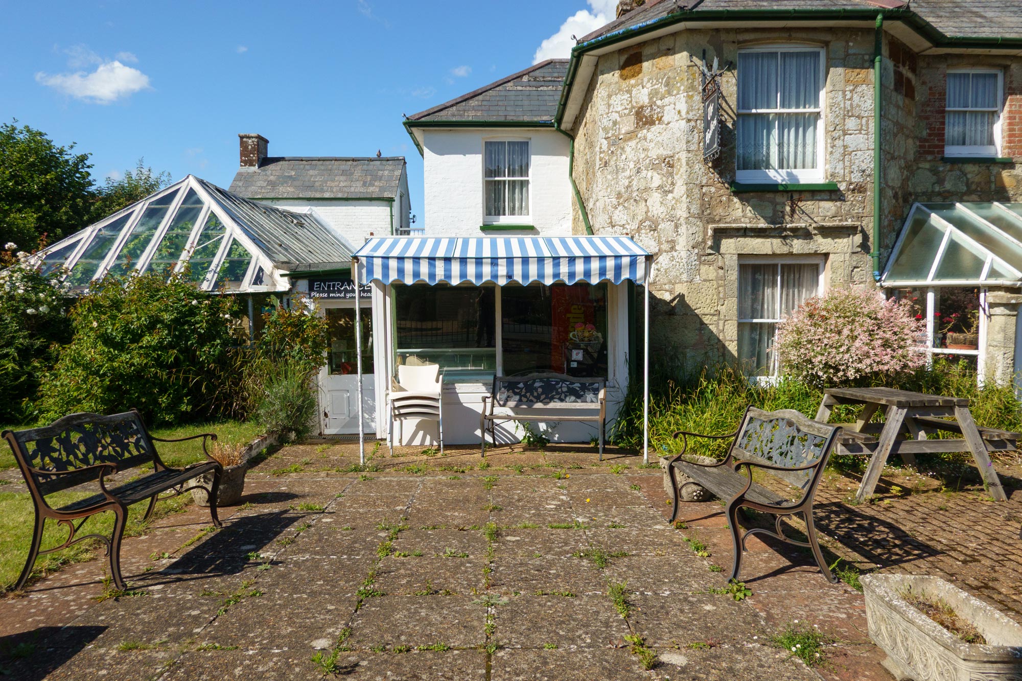 A small shop on the Isle of Wight with a striped canopy and benches out front.