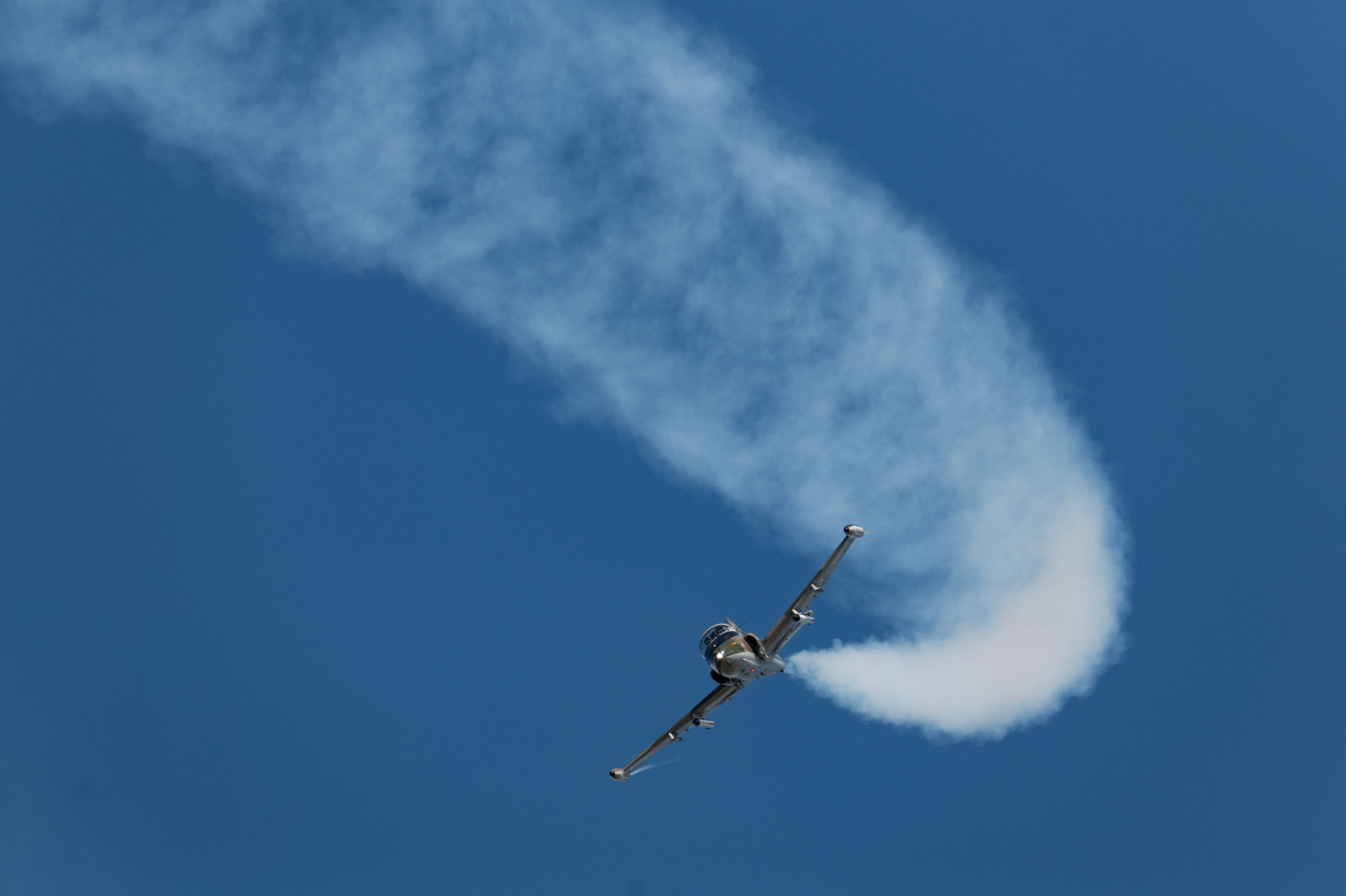 A plane flies in the sky, leaving a vapour trail after looping, photo by Amy Moore with the Panasonic S1R II.