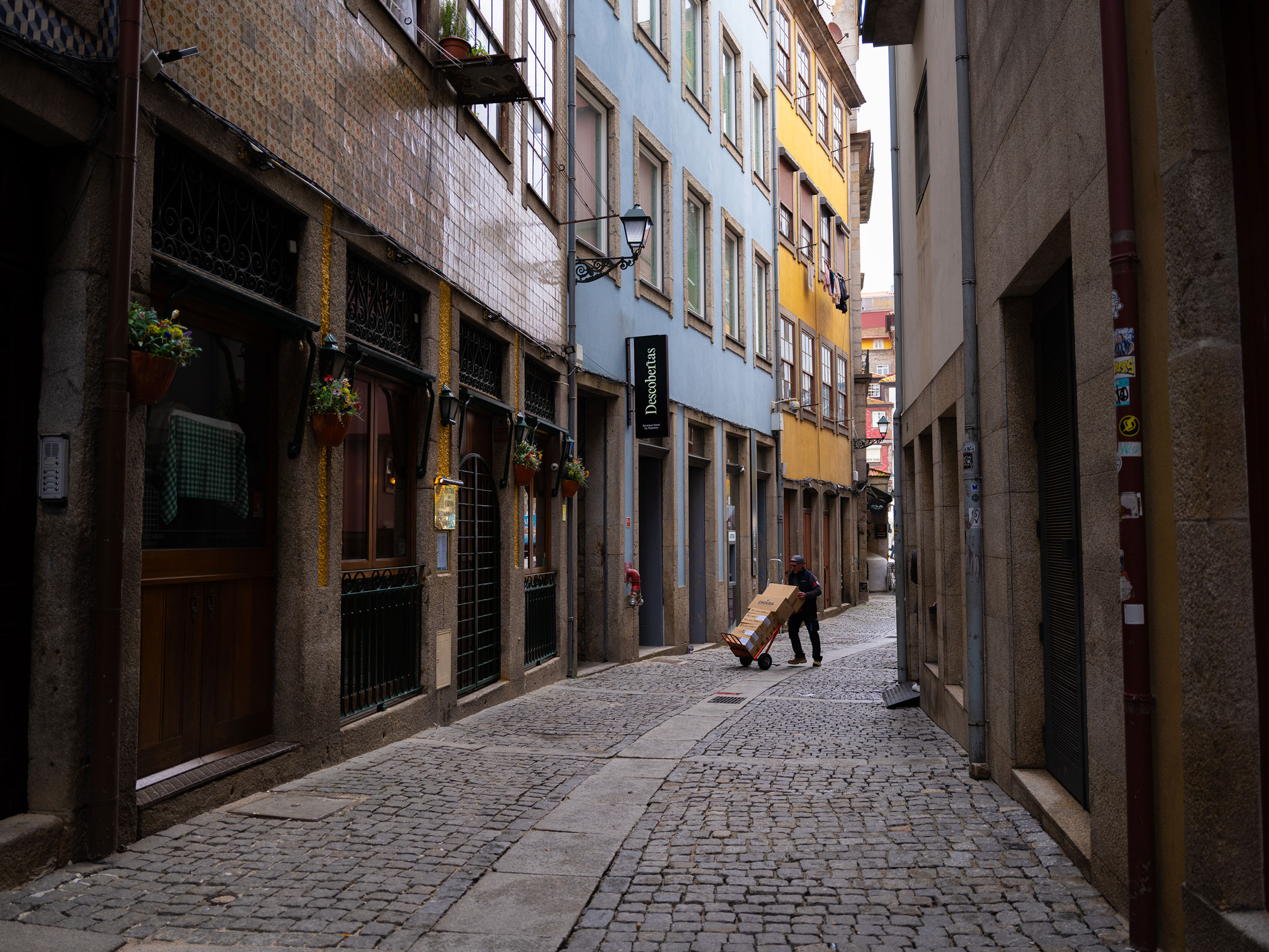 Person moving boxes in narrow street. Shot on the Fujifilm GFX100RF by Amy Moore.
