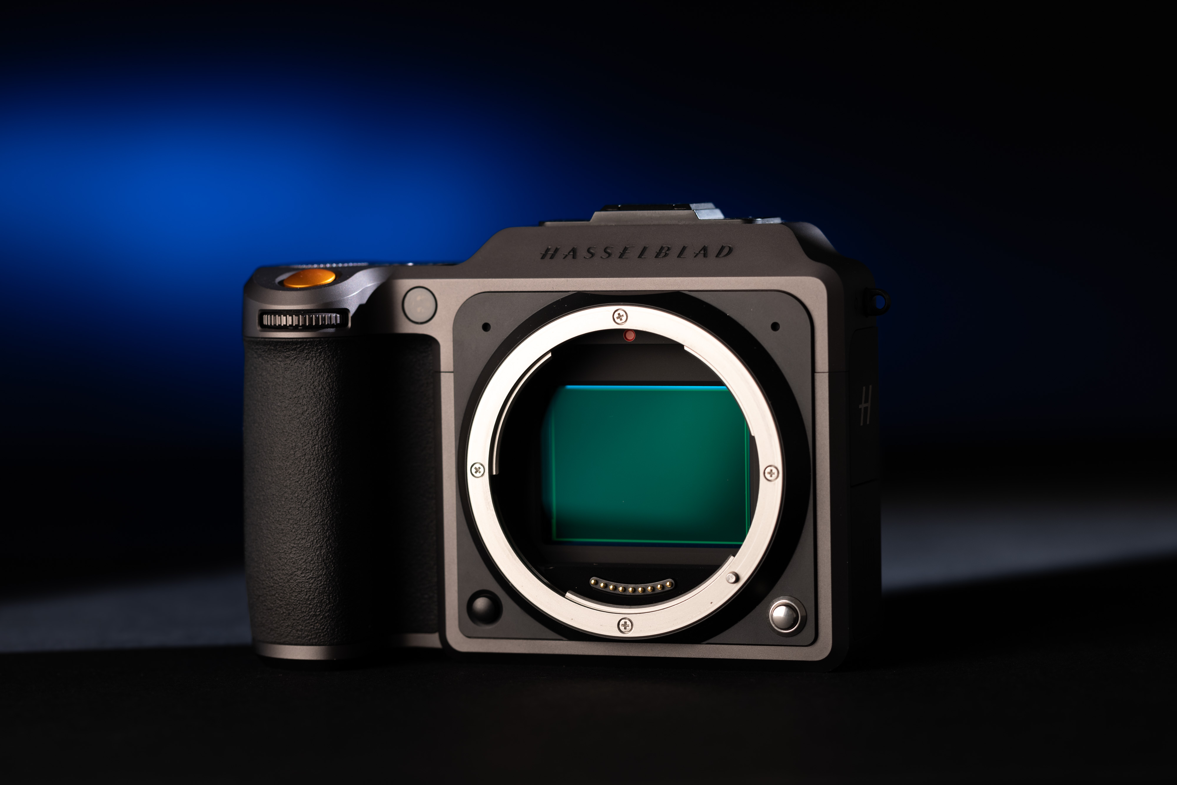 Een foto van een Hasselblad X1D op een donkere tafel met blauw licht op de achtergrond.