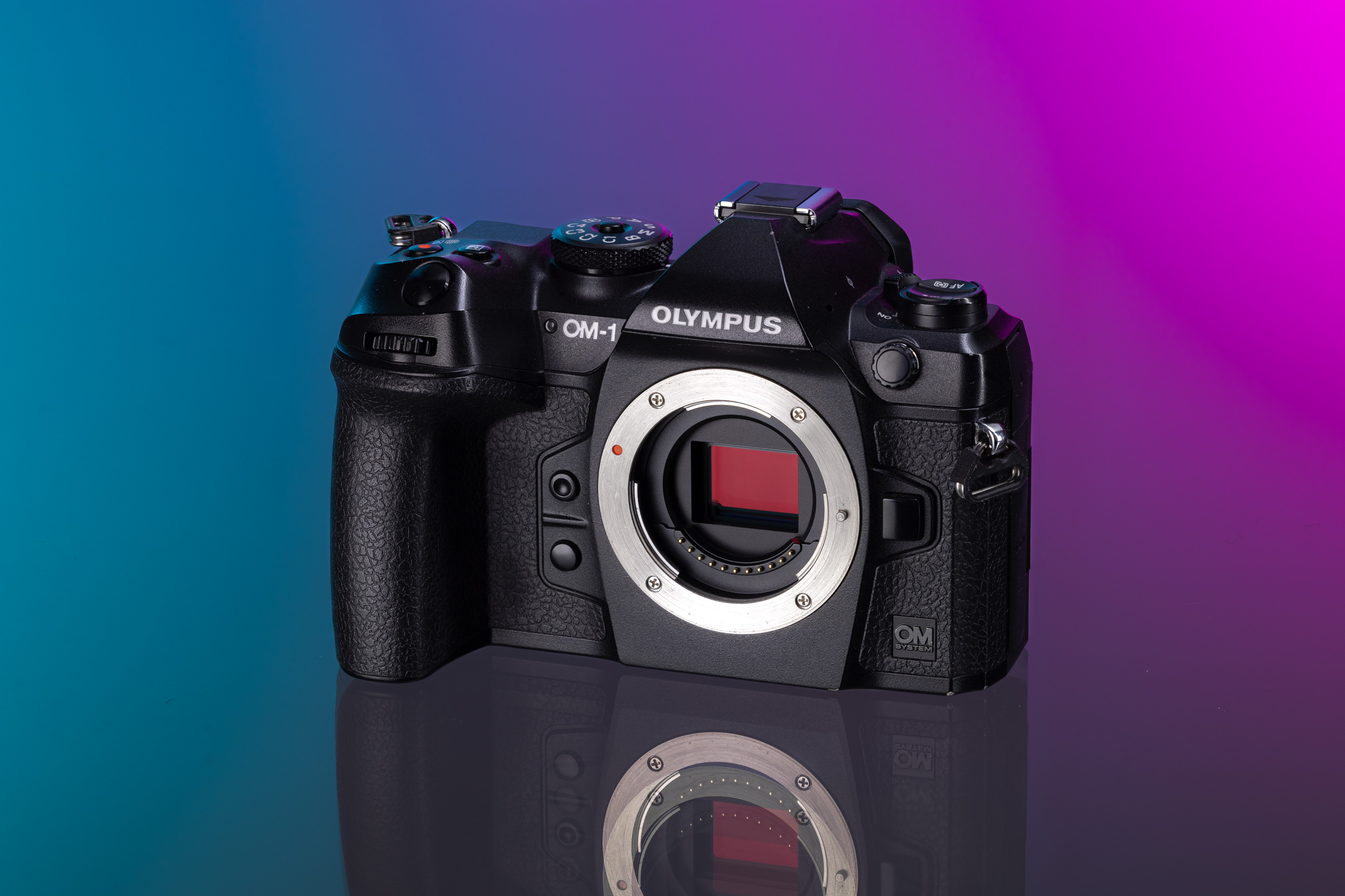 Tweedehands OM System OM-1 op een paarse en aqua achtergrond