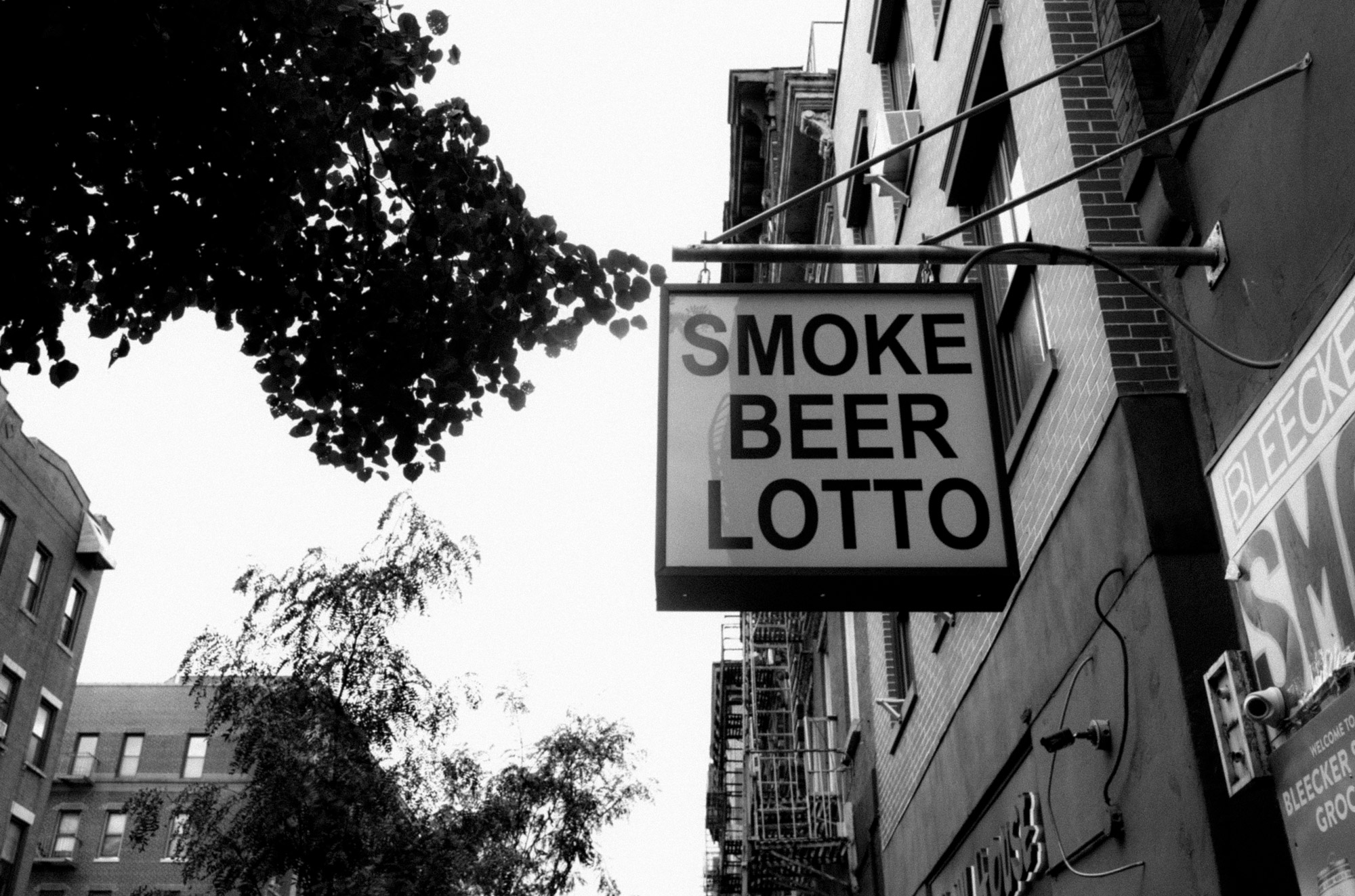 A black-and-white photo of a sign that says “Smoke Beer Lotto”