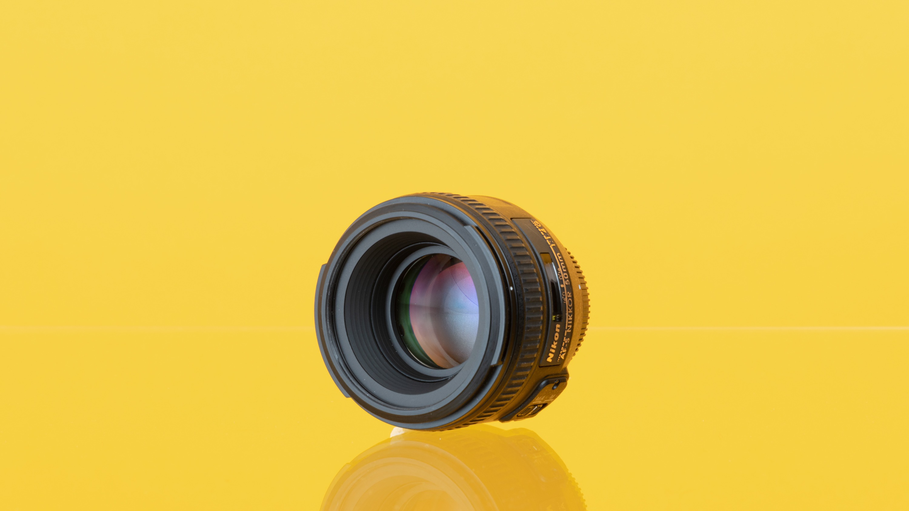 Tweedehands Nikon AF-S 50mm f/1.4G van MPB tegen een gele achtergrond