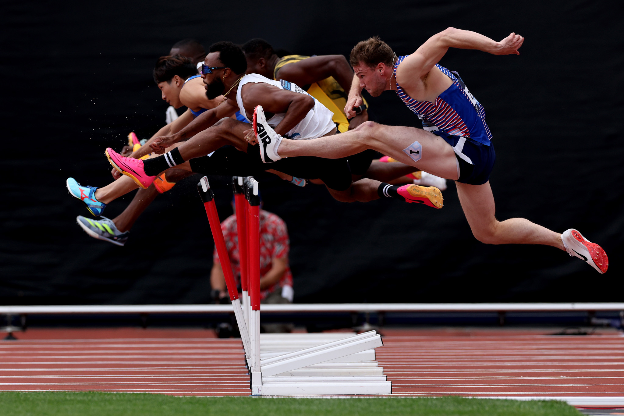 A group of hurdle runners all jumping over a hurdle at roughly the same time, creating a satisfying arc. By Shaun Brooks.