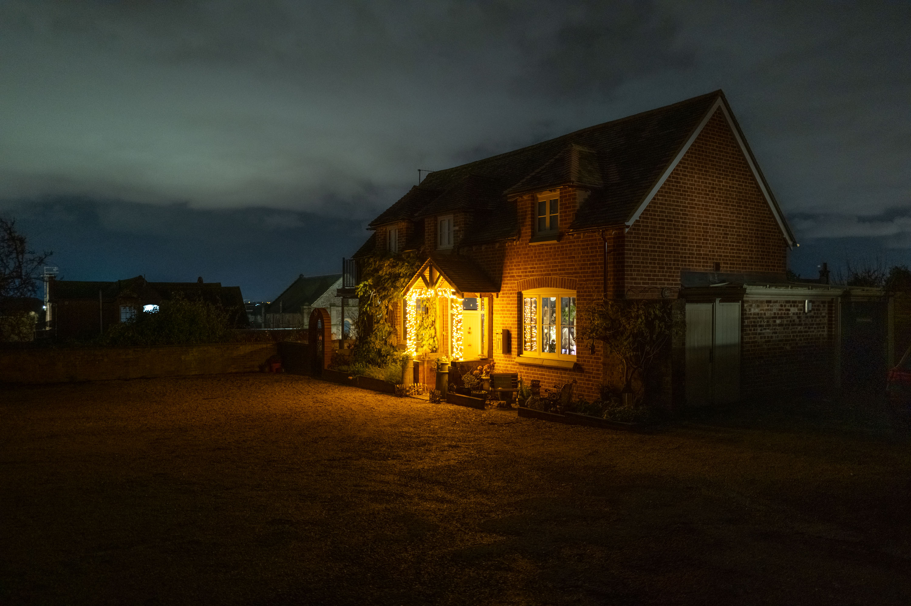 Ein Haus bei Nacht mit hellen Lichtern rund um den Eingang. ISO 1600