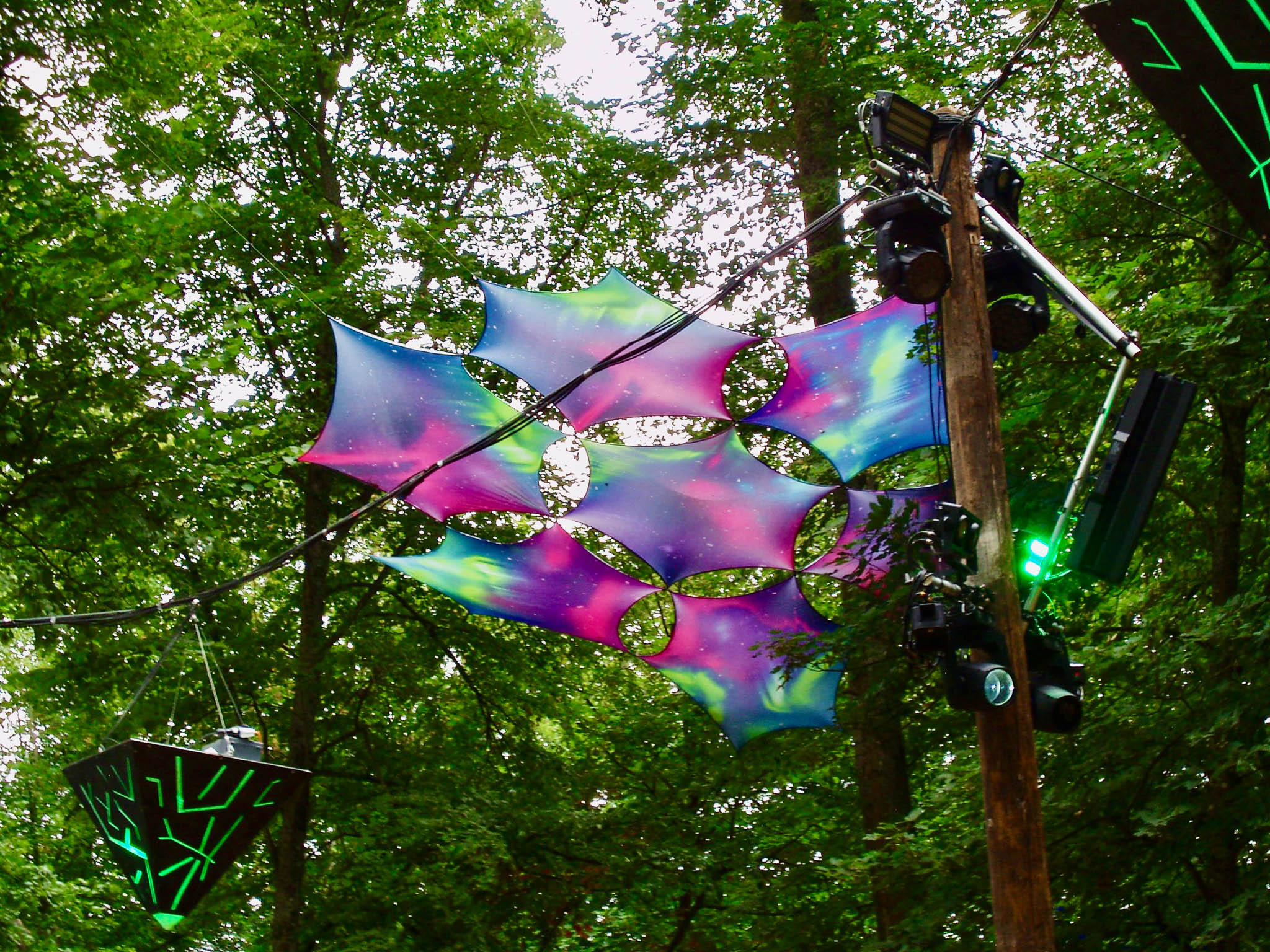 A psychedelic decoration in the trees at a music festival.