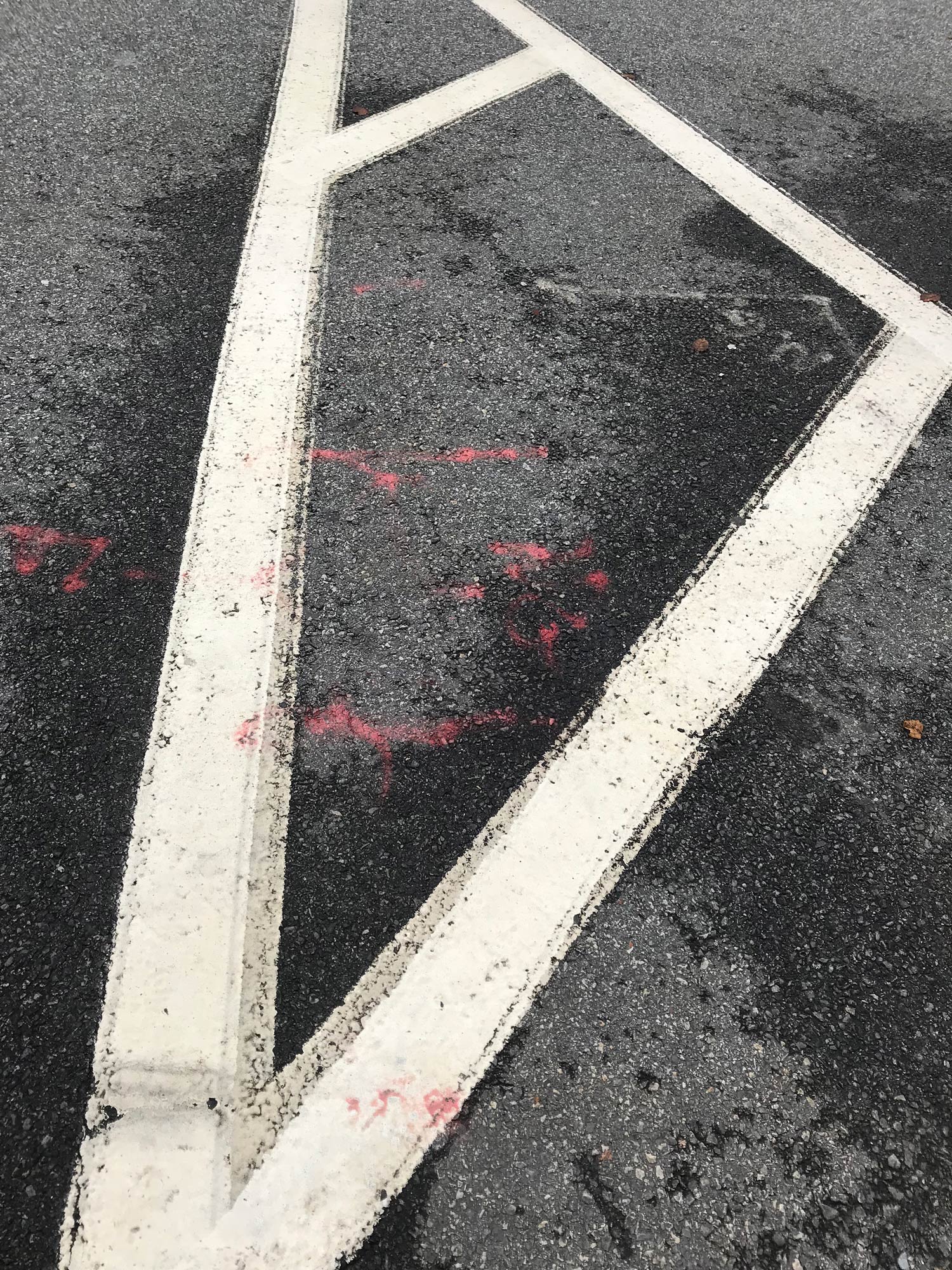 White road markings on a black road, with red panting marks over the top. Shot by Kim Fuller.