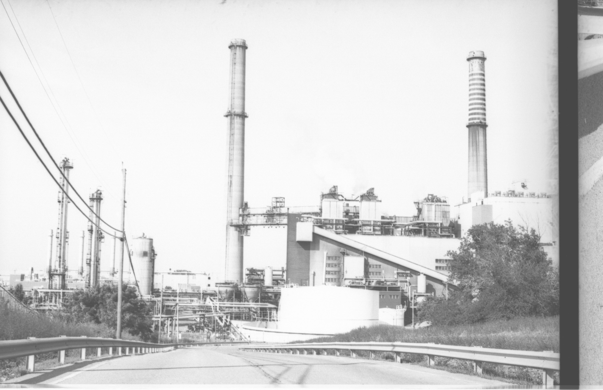 Een opvallende zwart-witfoto van de Kodakfabriek in Kodak Park, waarin het industriële landschap met torenhoge schoorstenen, fabrieksstructuren en de omliggende infrastructuur is vastgelegd.