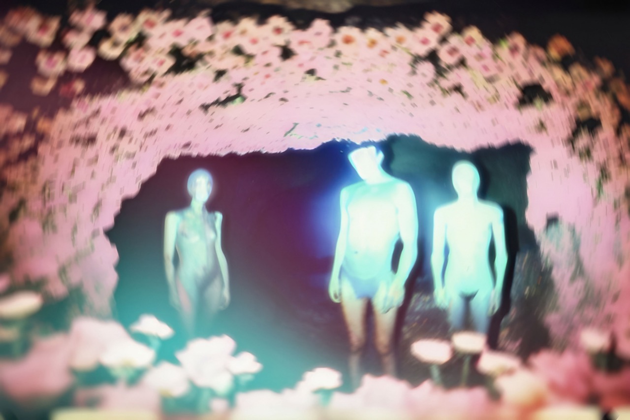 Een beeld van 3 mensachtige figuren gezien door een cirkel van roze bloemen. Een werk genaamd Perception van kunstenaar Claudia Fuggetti