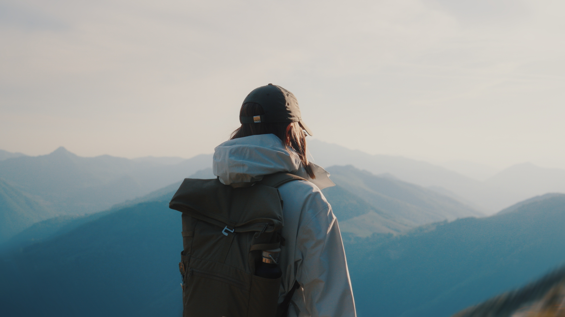 Person with a trekking backpack looking at a mountainous landscape