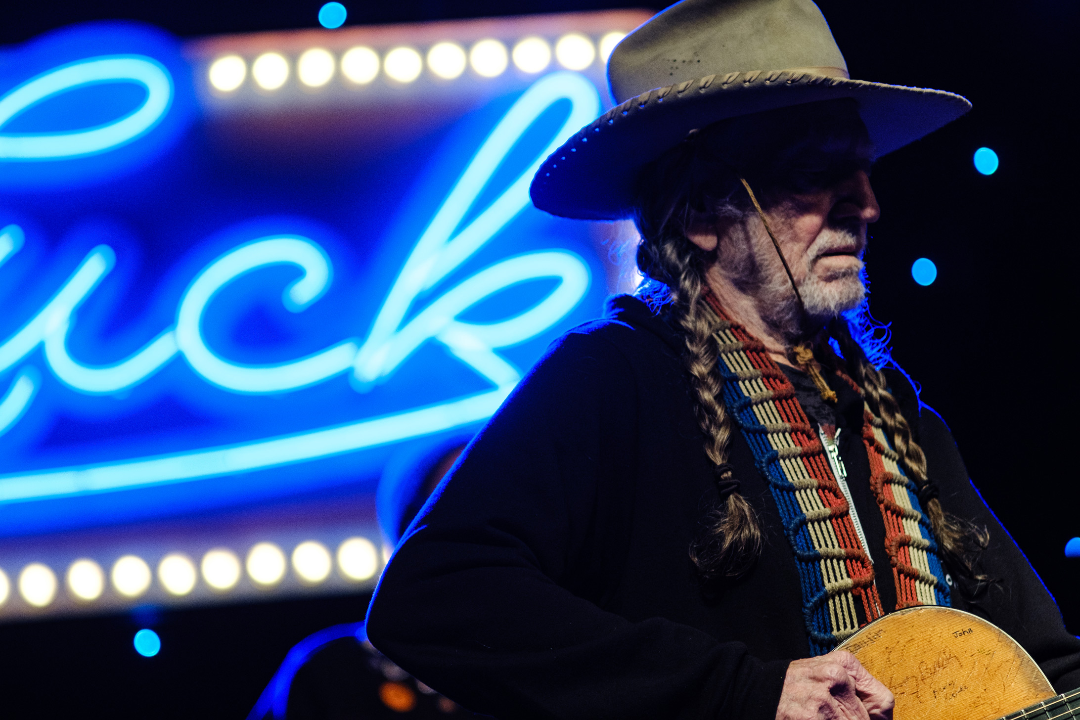 Willie Nelson in a cowboy hat and braids on stage performing in 2019. Photo taken by James Joiner on a Fujifilm X-T3.