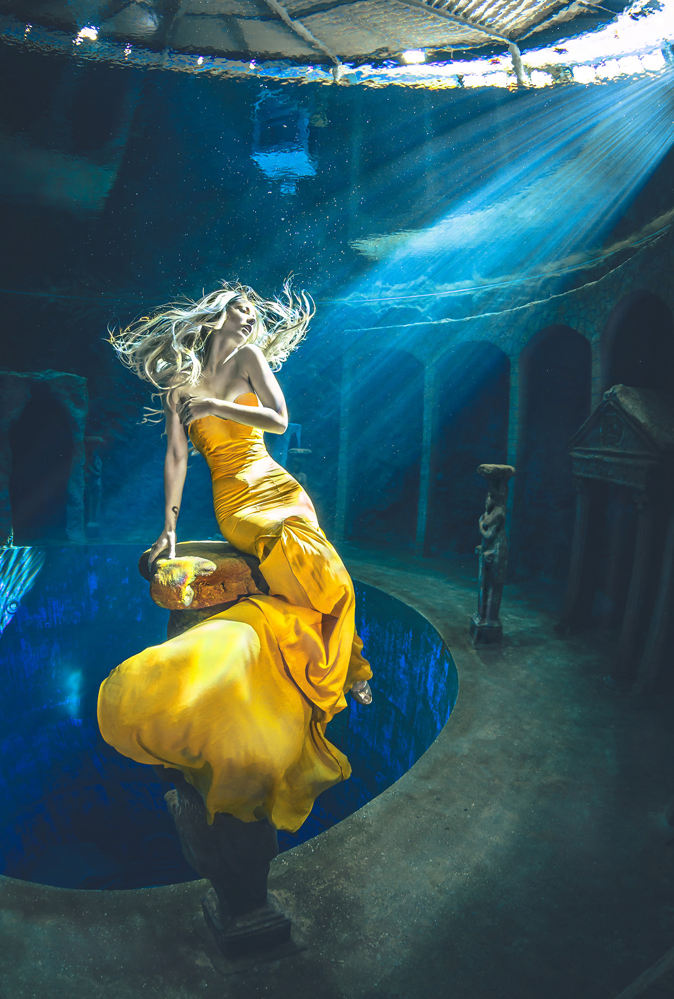 Ein Unterwasserbild von einer Frau die ein gelbes Kleid trägt und von ruinen umgeben ist. Sonnenstrahlen unter Wasser einfangen.
Die Sonnenstrahlen unter Wasser werten ein UW Foto enorm auf. Nur in einem bestimmten Winkel sind diese jedoch unter Wasser sichtbar und können eingefangen werden.