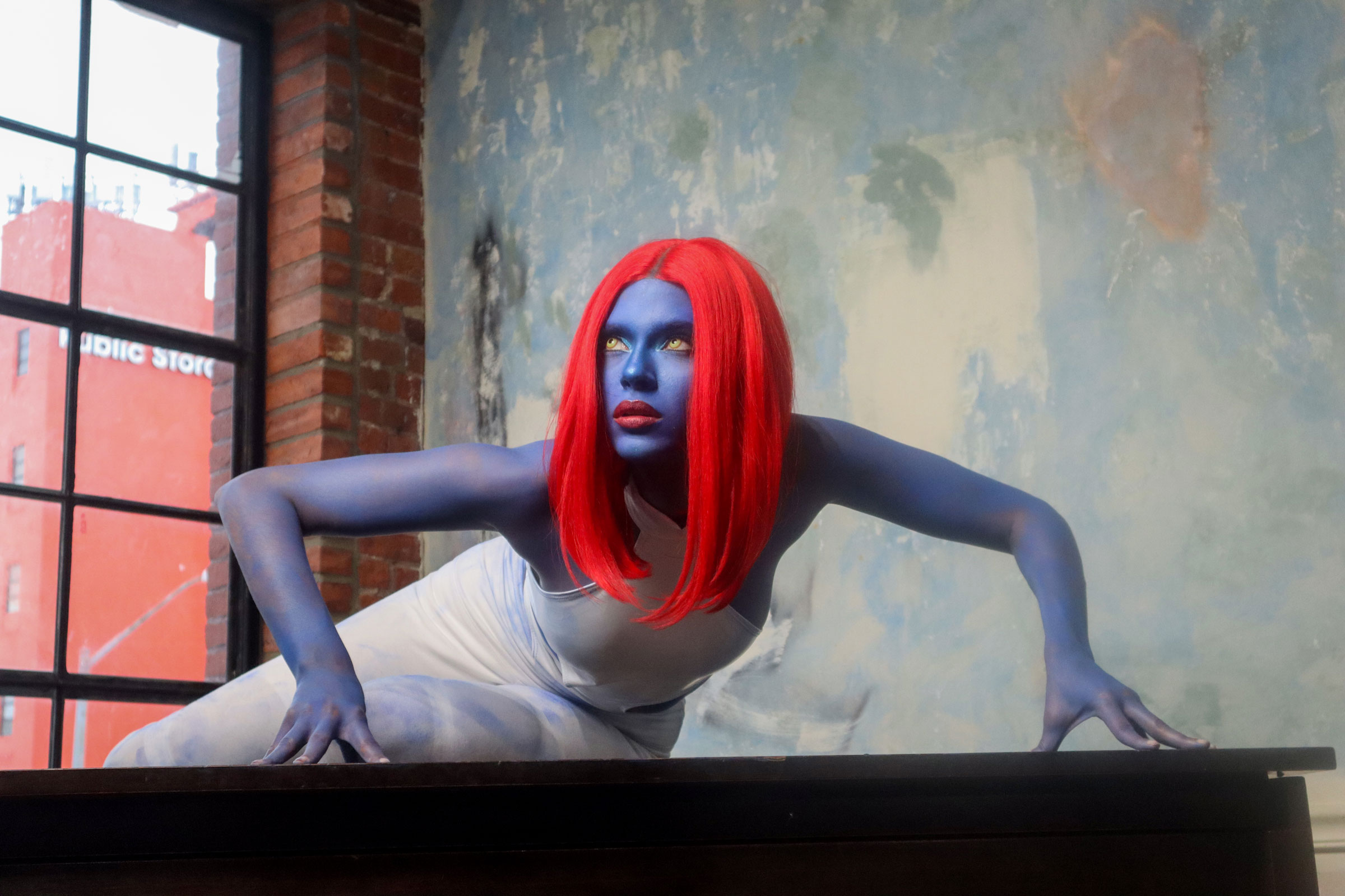 Mystique cosplayer poses on a piano.
