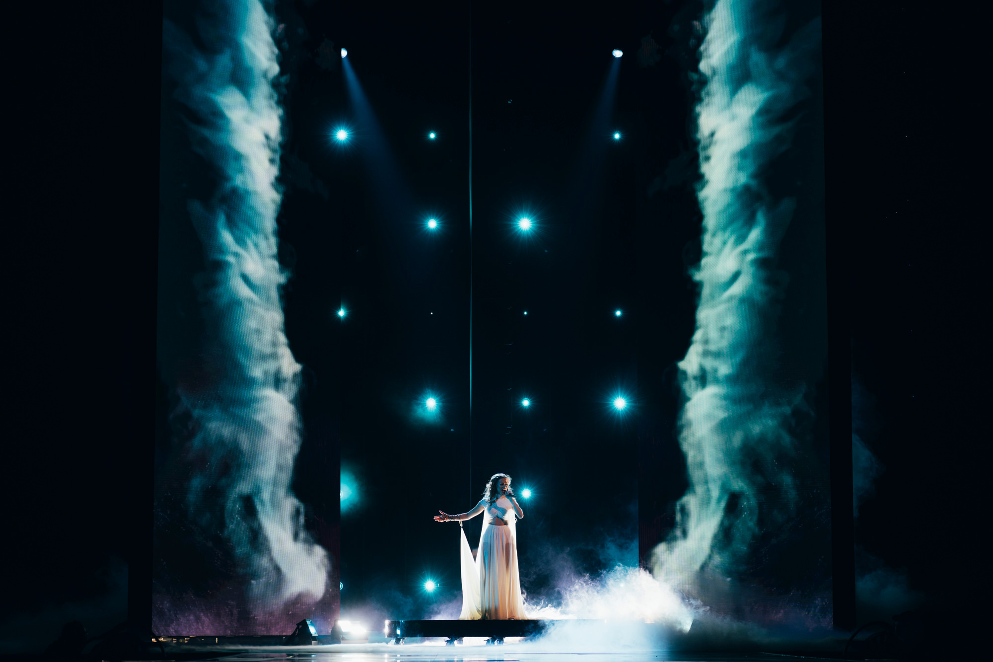 A performer in a white dress on stage at Eurovision 2023, with smoke either side of them, shot by Sarah Louise Bennett with the Nikon Z7 II.

