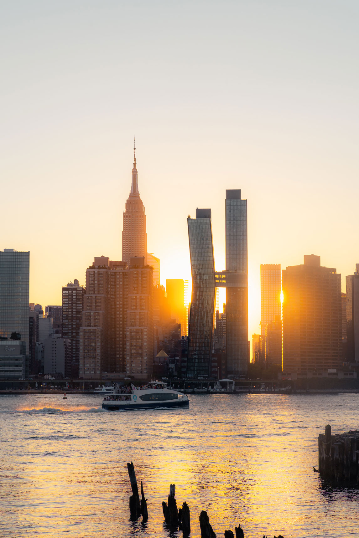 Ein Foto der Skyline von New York City bei Sonnenuntergang mit einem Boot auf dem Wasser.