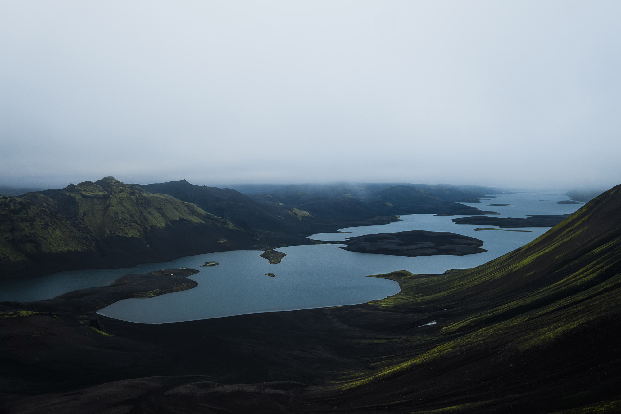 A lake surrounded by green mountains in Iceland with a grey sky, shot by Paul Watson with a Panasonic S1R