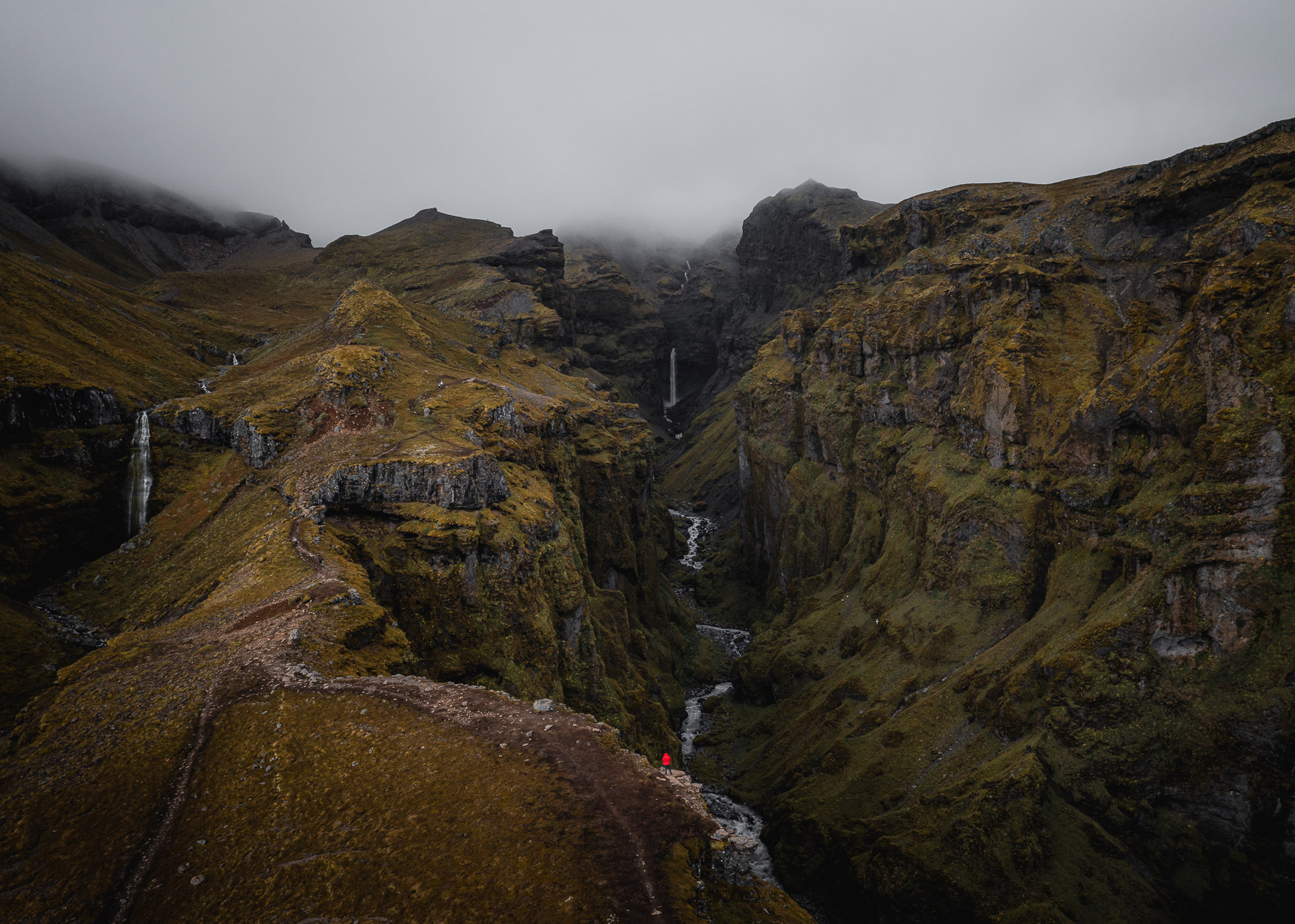 A drone photo of a river running through a valley in Iceland, the hillsides are covered in moss and there is a waterfall in the foreground, shot by Paul Watson with a DJI Mavic 2 Pro