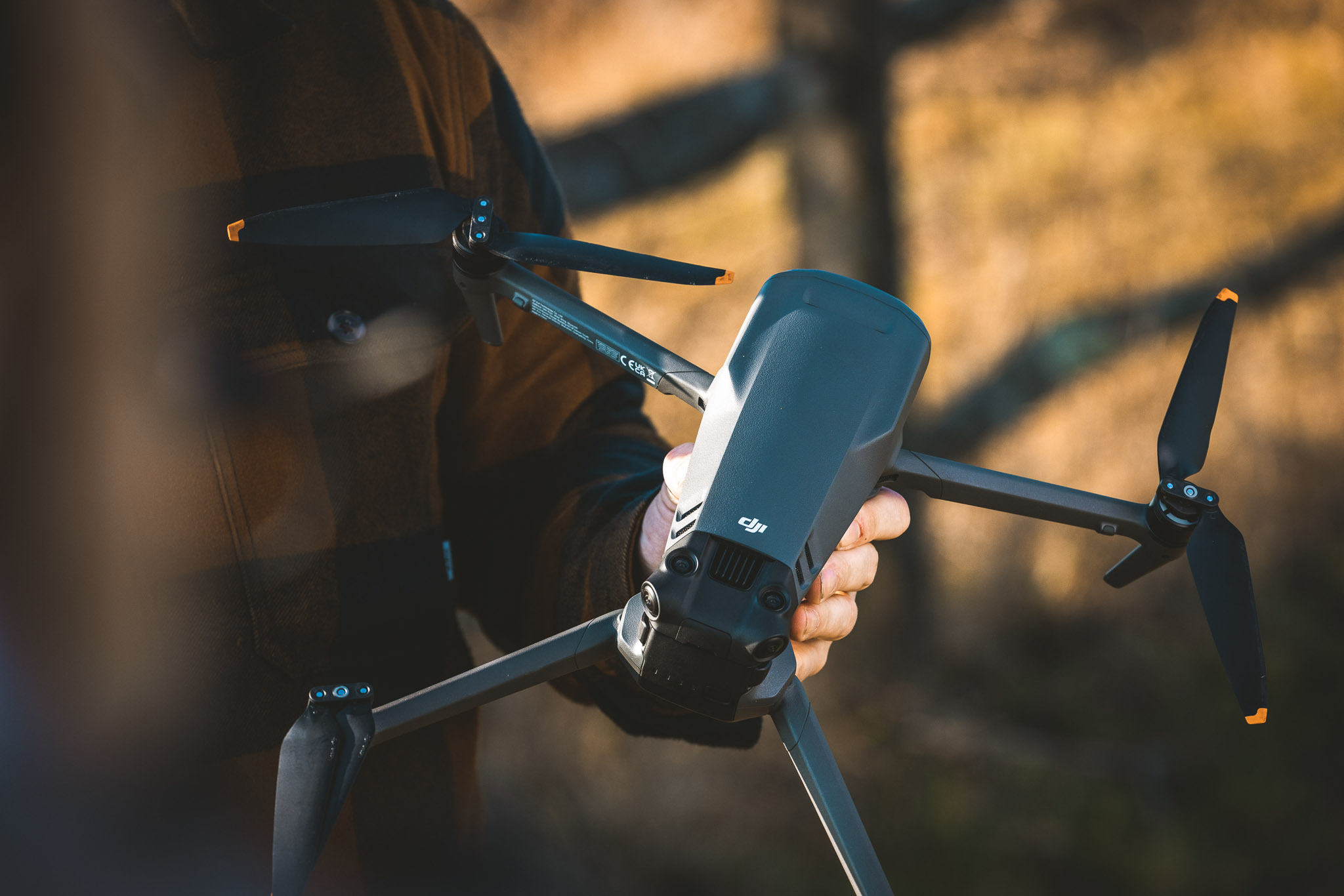 Close-up of a DJI Mavic 3 drone being held by hand, highlighting the design and rear obstacle sensors.