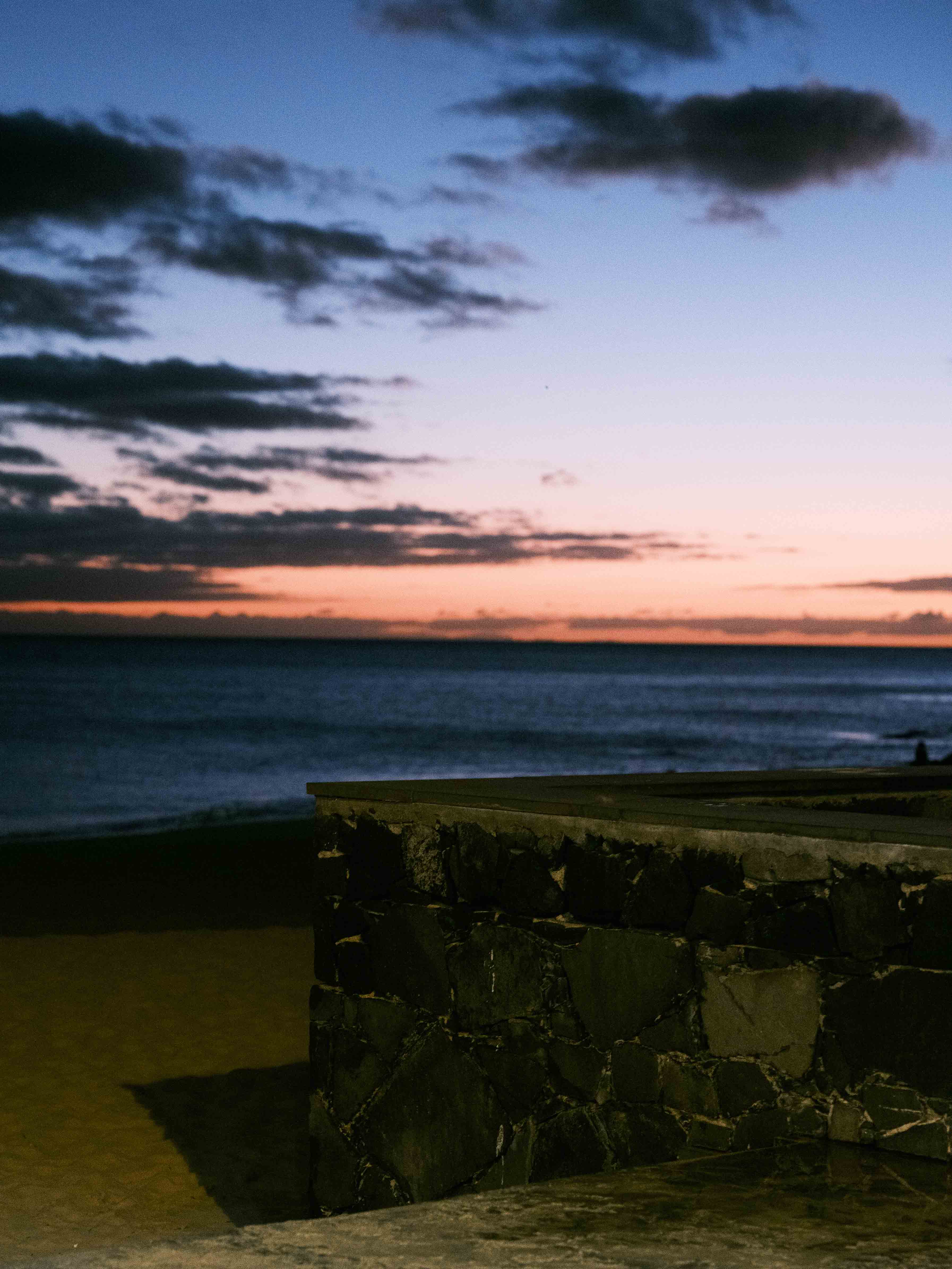 Image of a sunset on the beach with a promenade wall in the foreground. Taken on the Fujifilm GFX 50R by Connor Redmond. 


