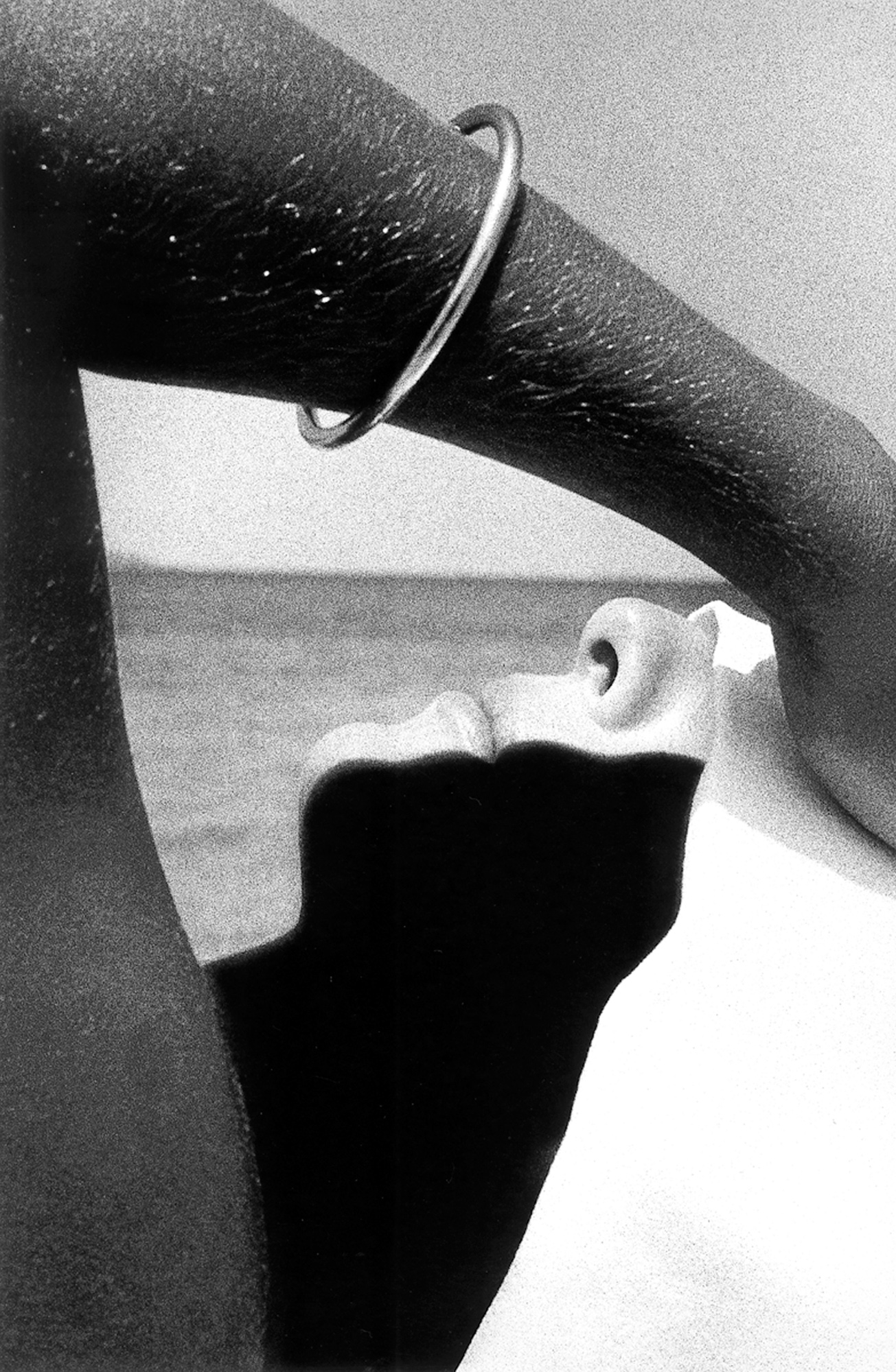Ralph Gibson, imagen en blanco y negro del rostro y el brazo de una mujer enmarcando el mar.