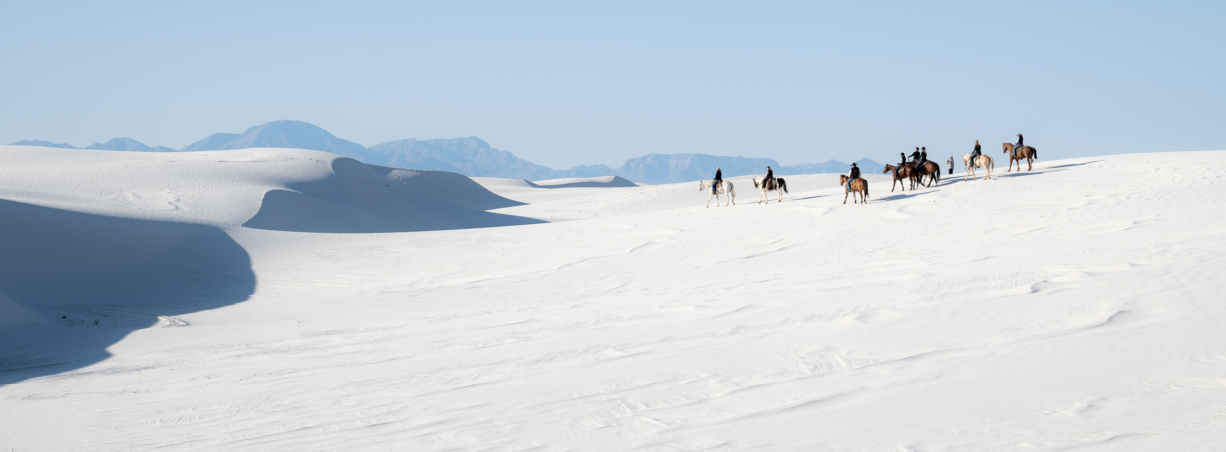 Horizontal wide image of White Sands National Park in New Mexico, USA with people on horses, taken by Alex Armitage on a Nikon Z8.

