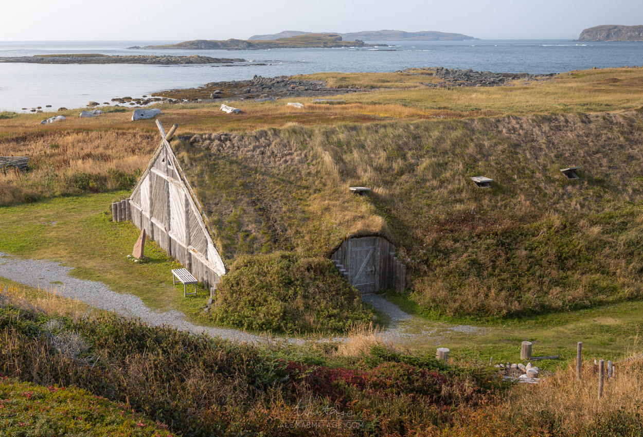 A peaceful building sits in a green field by the seaside.