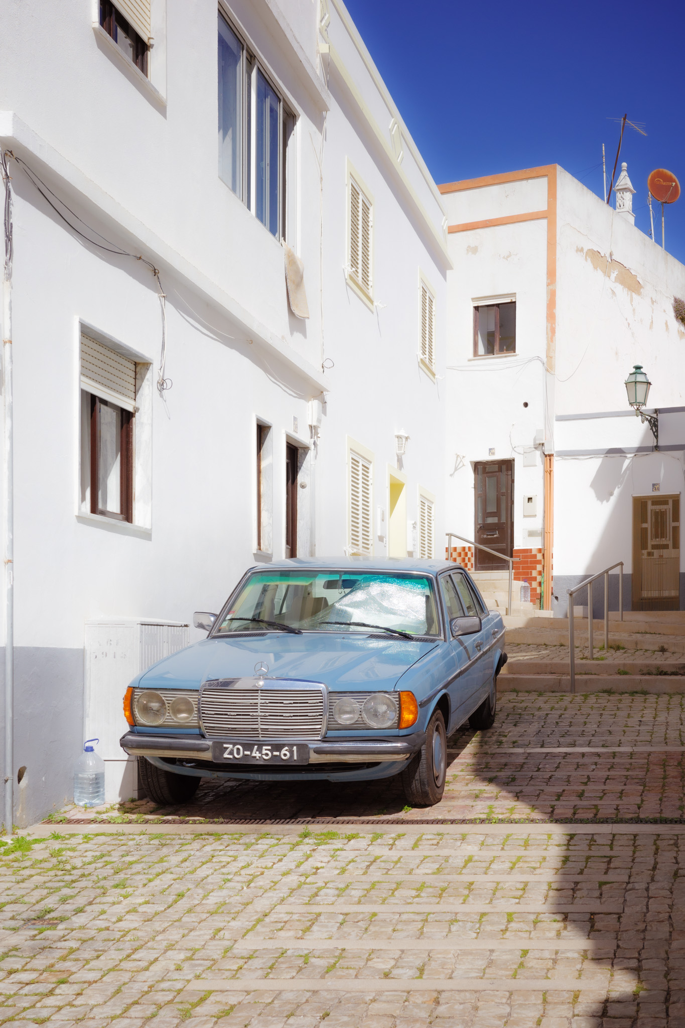 Ein blauer Mercedes-Oldtimer, geparkt in einer alten Straße in Albufeira, Portugal. Von Connor Redmond.