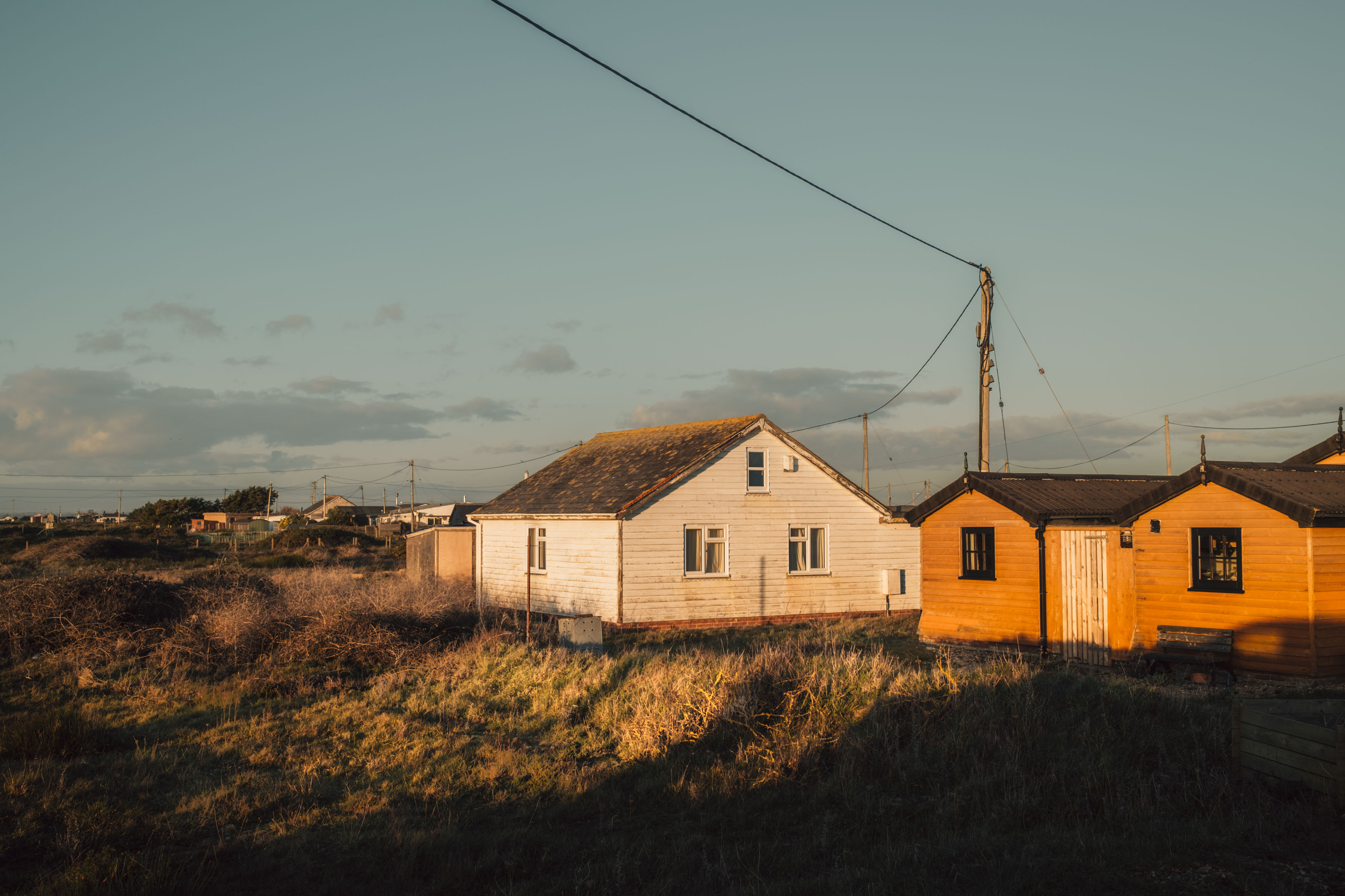 Een groep houten bungalows bij zonsondergang in Dungeness, Kent, Verenigd Koninkrijk, gefotografeerd door Ian Howorth.