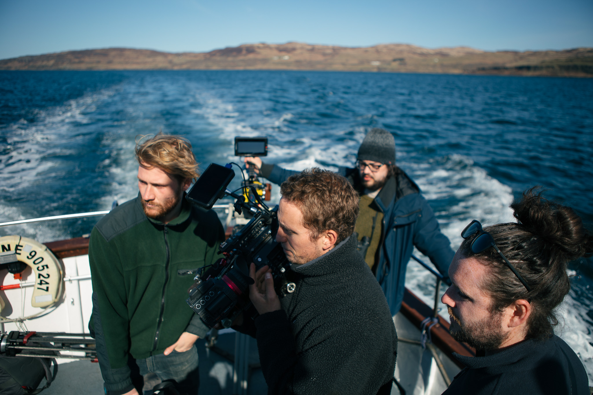 Un groupe de personnes à l'arrière d'un bateau avec un appareil photo.
