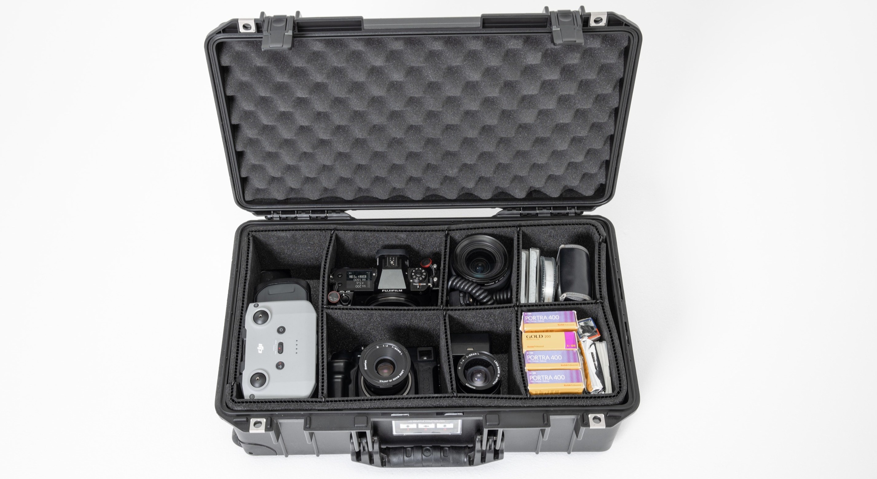 Een foto van de binnenkant van de Peli 1535 Air Case, gevuld met camera's, lenzen, drone, filmrolletjes en accessoires, geschoten tegen een witte achtergrond.