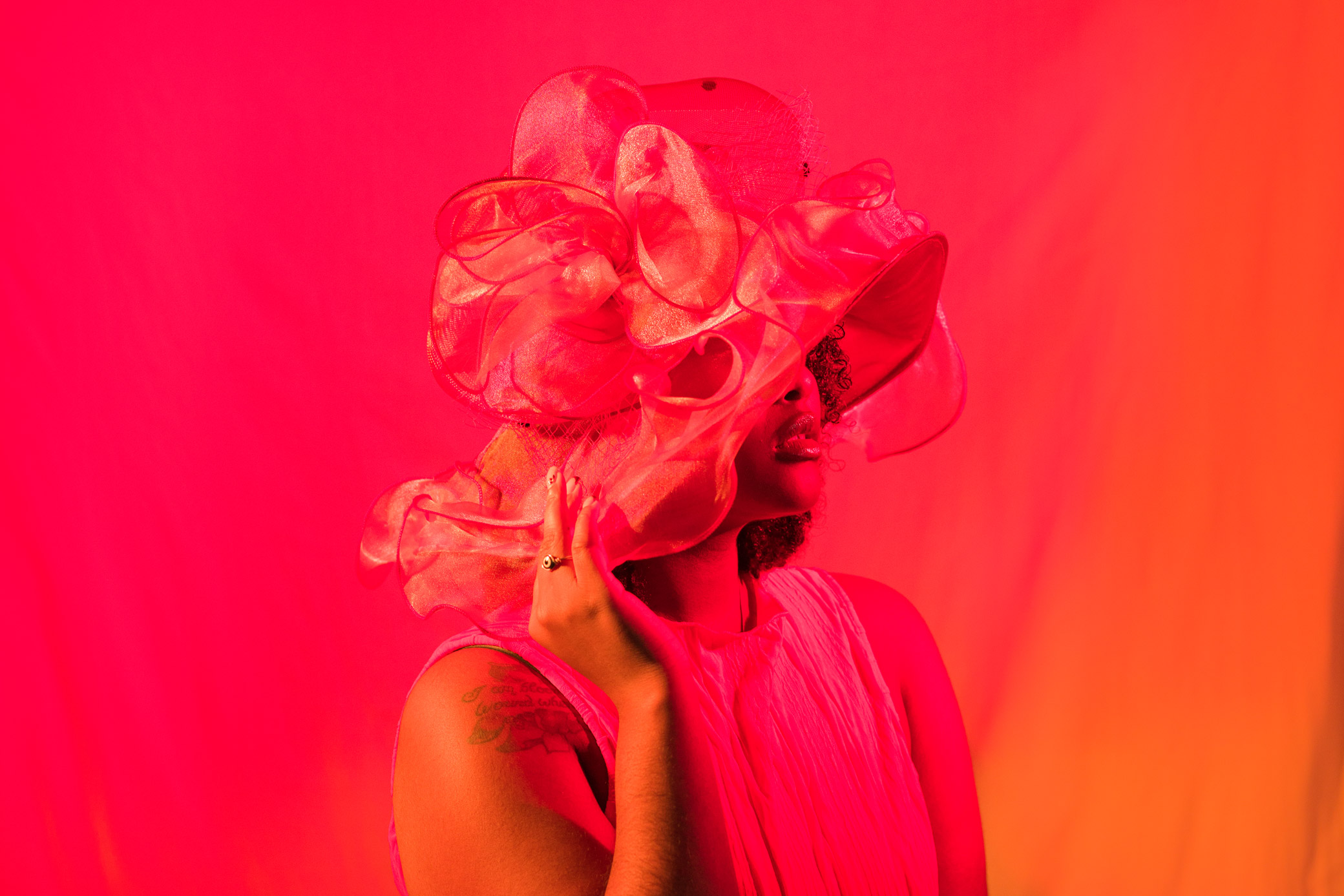 Person in front of red backdrop with hat on, by Kaylah Sambo on a Hasselblad X1D-50c.