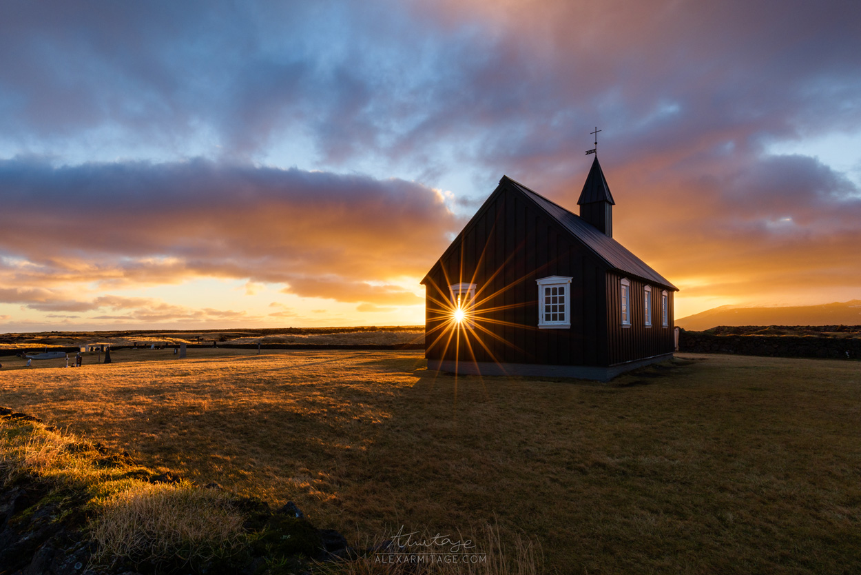 A small building sits in a field at dusk.