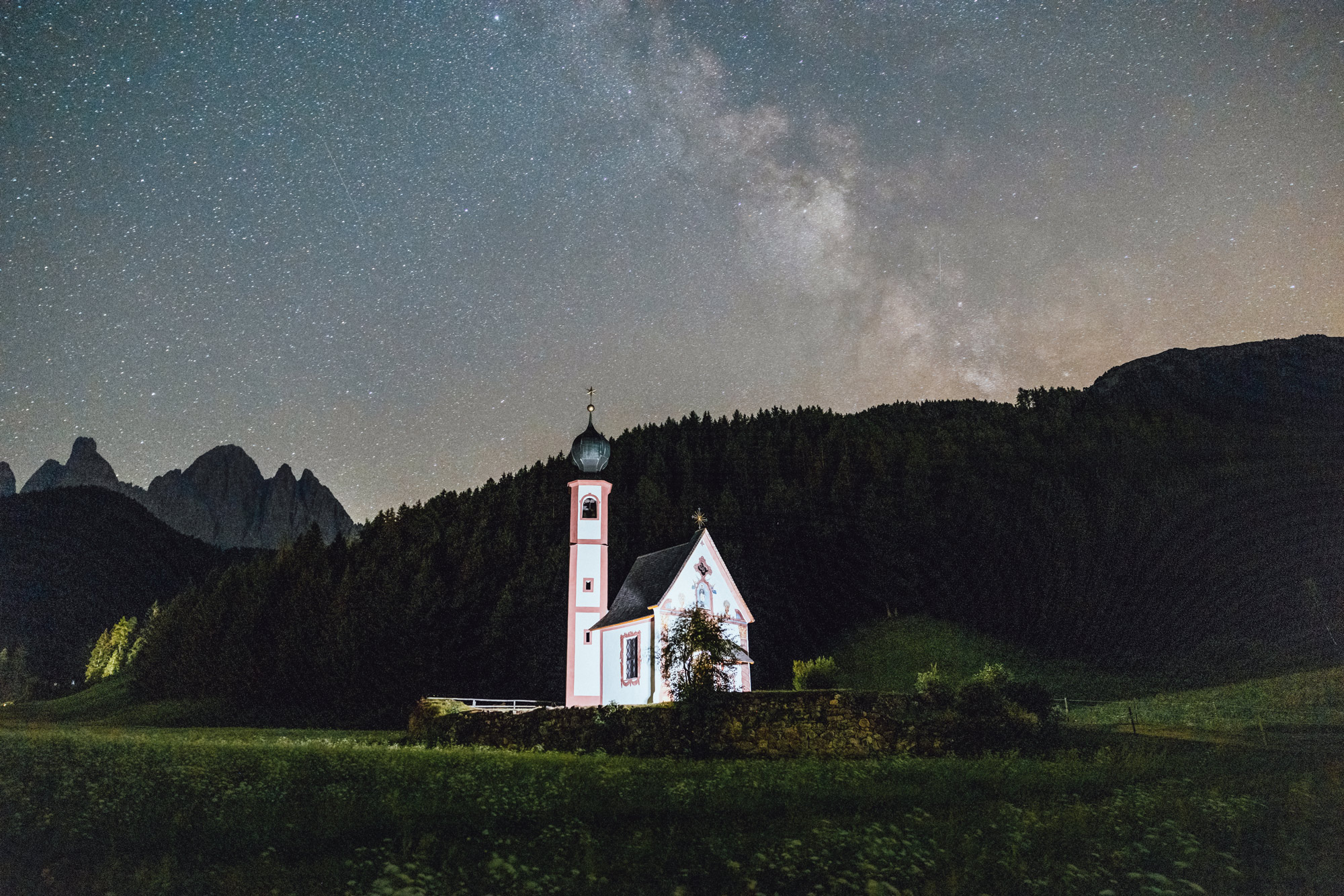 A white church with hills, trees and a star-filled sky in the background, shot by Jacob Murray with a Canon EOS R5 and RF 24-70mm f/2.8.