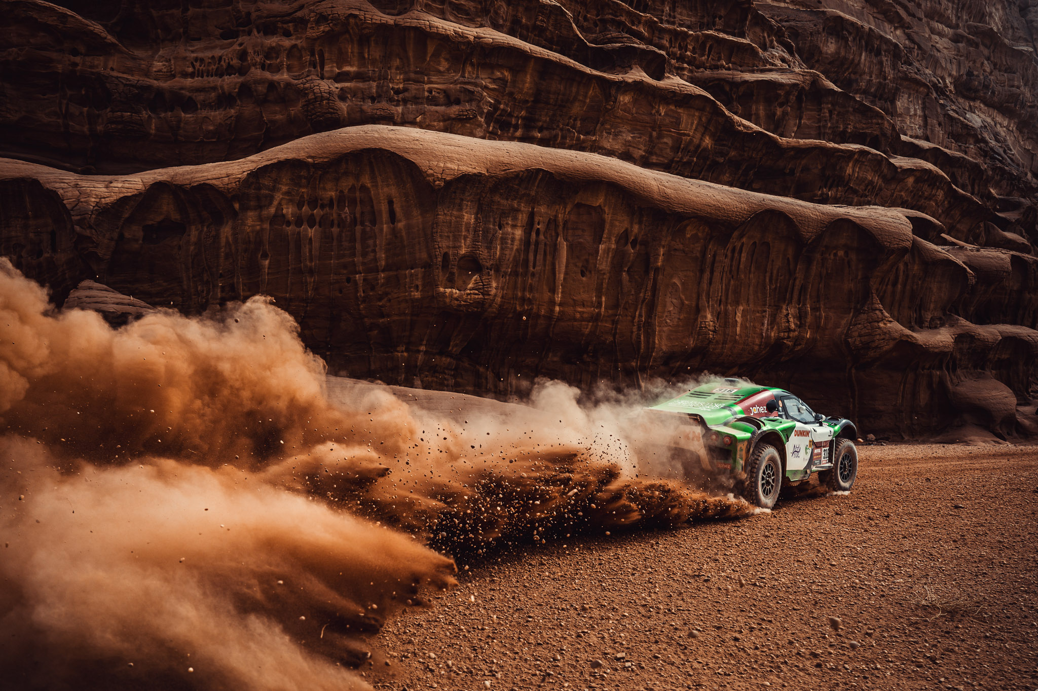 Yasi Seidan, Rally Dakar, een auto die snel door zanderig en ruig terrein rijdt en een enorme stofwolk achterlaat, gefotografeerd door Marian Chytka