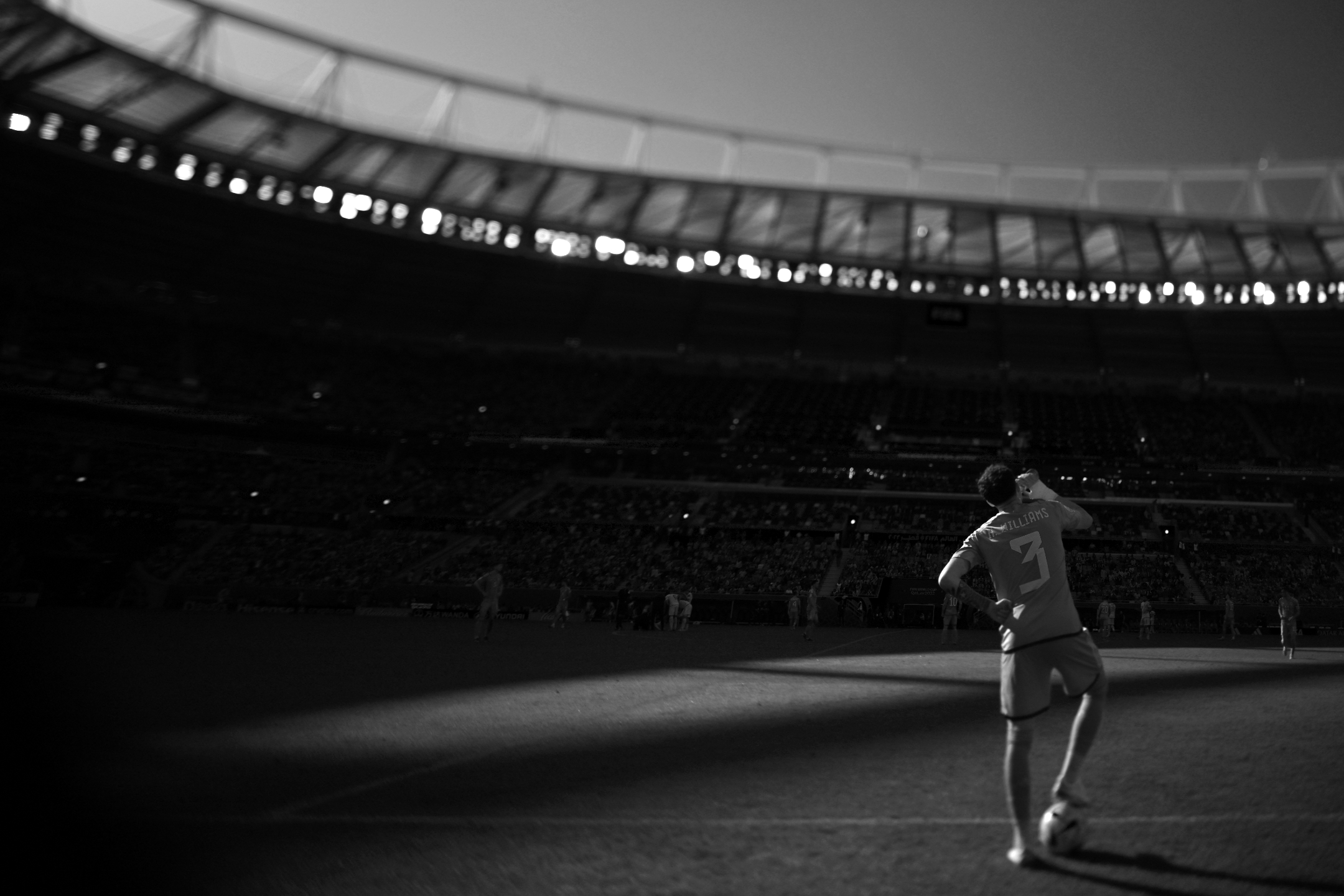 Schwarz-Weiß-Tilt-Shift-Foto des walisischen Verteidigers Neco Williams, der den Ball bei der 2:0-Niederlage seiner Mannschaft gegen den Iran bei der Weltmeisterschaft 2022 stoppt, aufgenommen mit einer Nikon Z9 und einem Nikon PC-E NIKKOR 24mm f/3.5D ED von Ryu Voelkel.