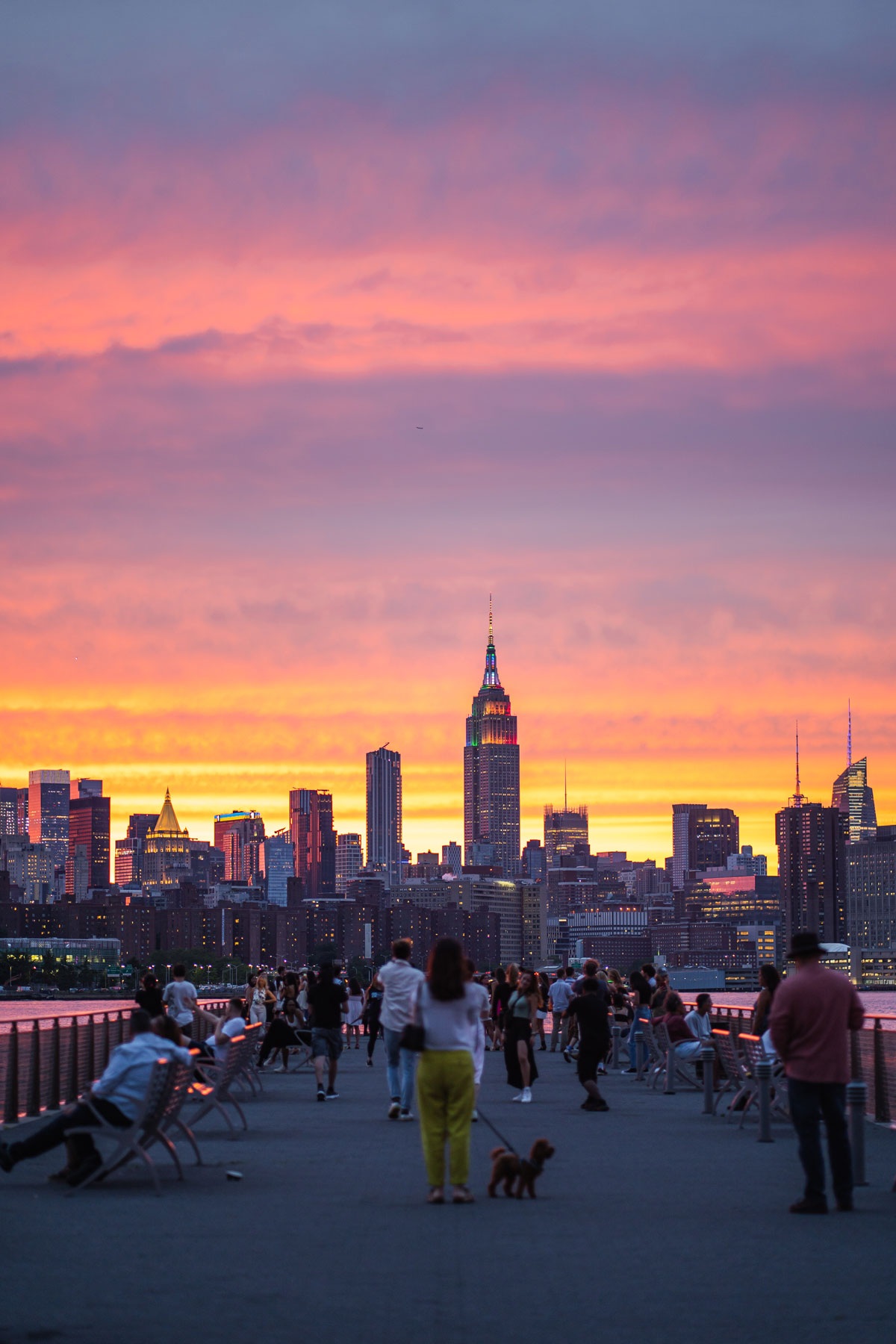Ein Foto von Menschen, die am North 5th Street Pier sitzen und stehen, während die Sonne in New York City untergeht.