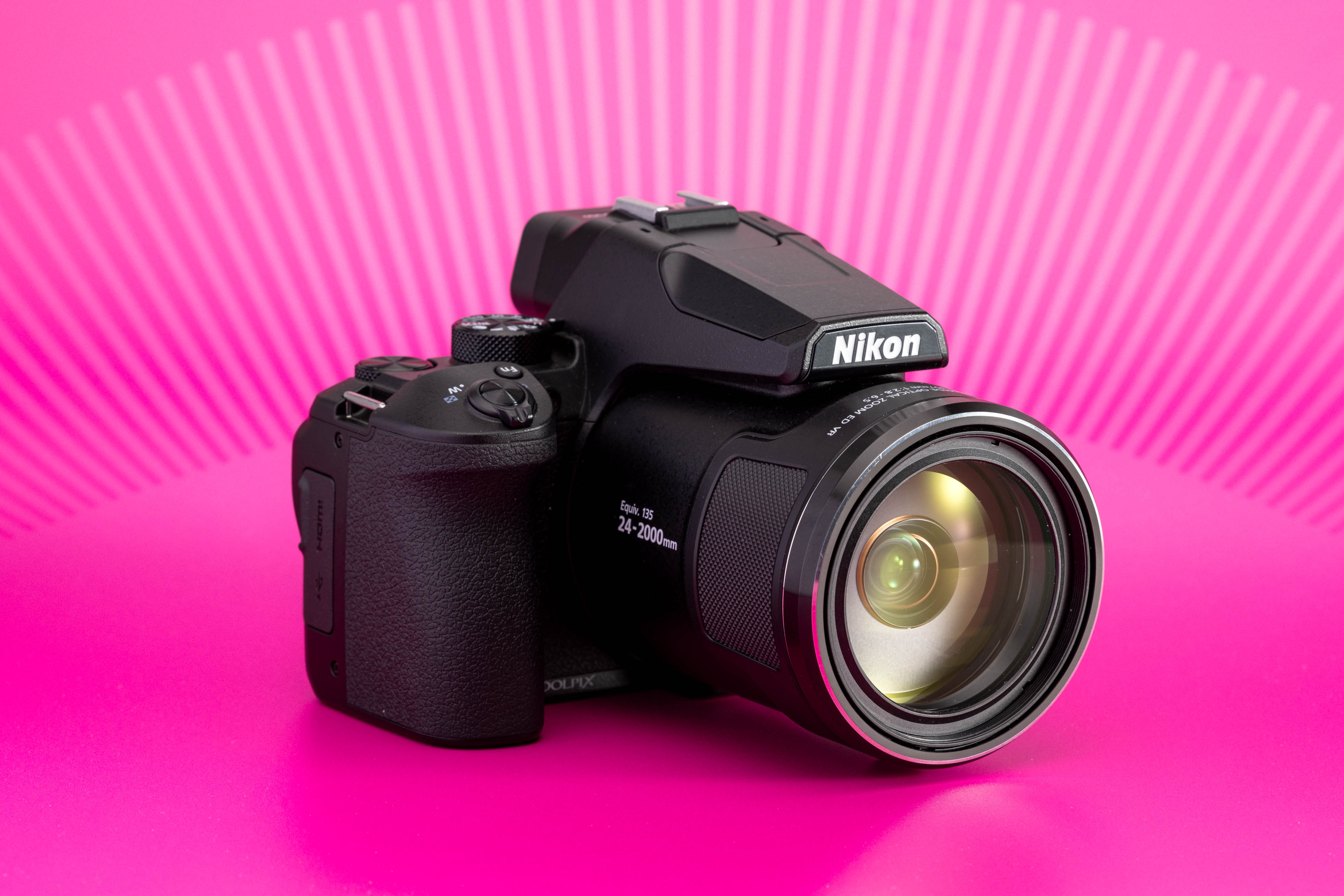 Nikon Coolpix P950 fotografiada sobre fondo rosa, con objetivo zoom integrado. Foto de Connor Redmond