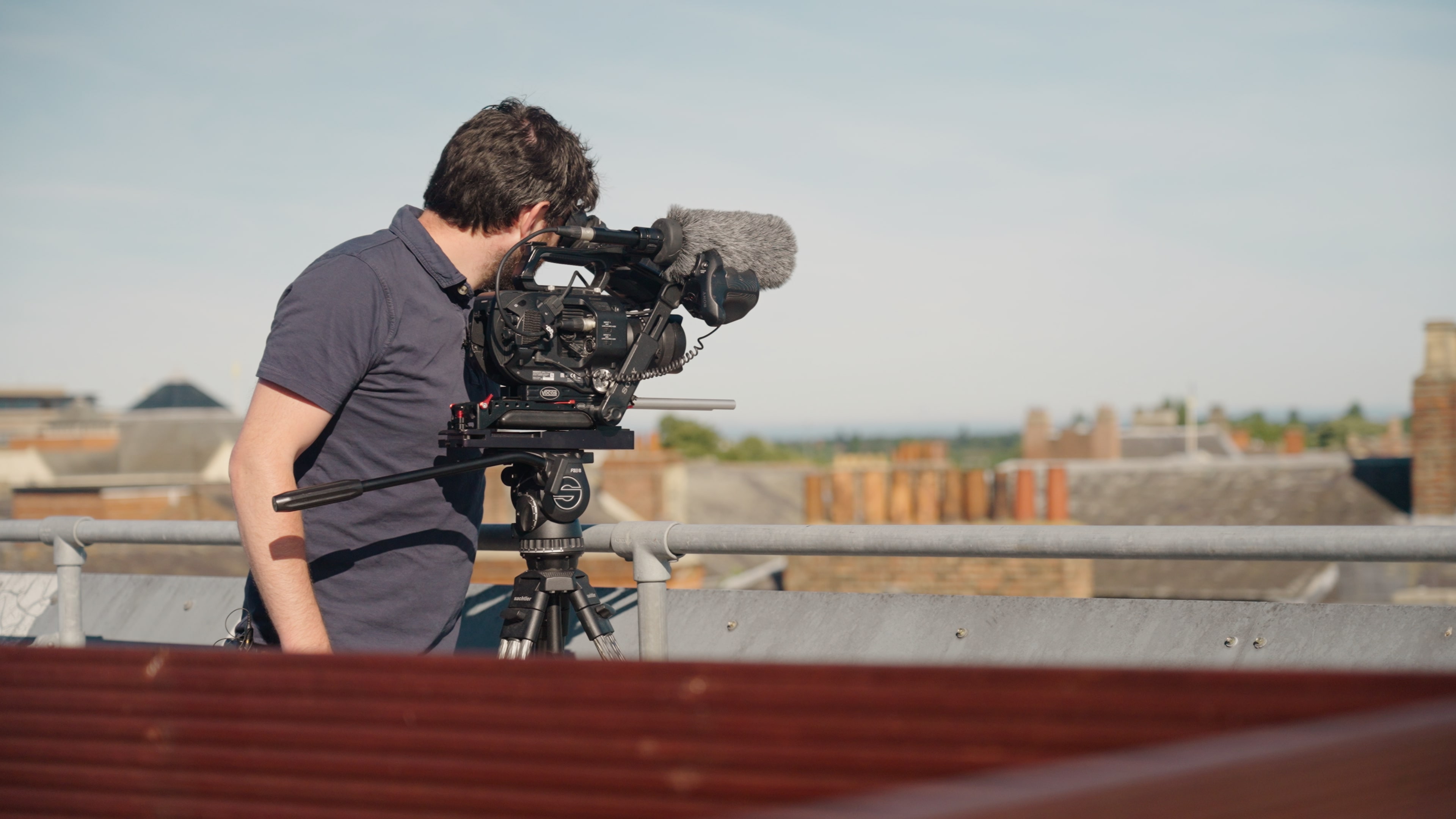 Le producteur-réalisateur de télévision Steve Morgan utilise un Sony FS7, monté sur un trépied, devant des garde-corps sur un toit.